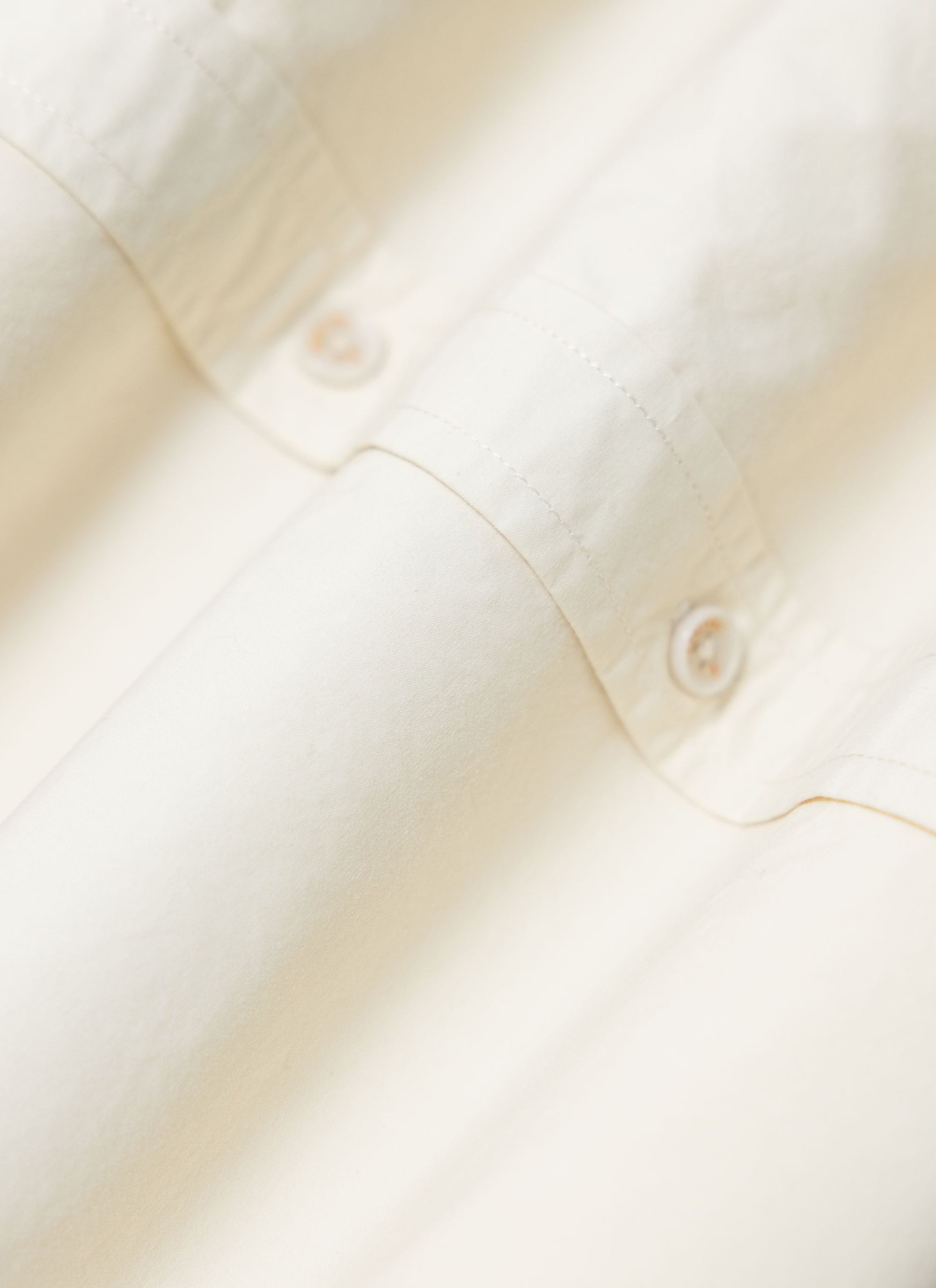 A close-up of the Percival Boxy Cropped Clerk Shirt in ecru, showing the lightweight paper touch cotton and buttons.