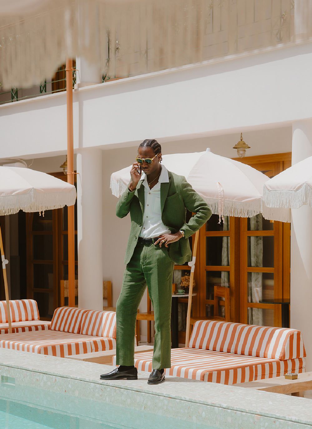 Percival forest green tailored linen trousers and blazer on a model by a pool.