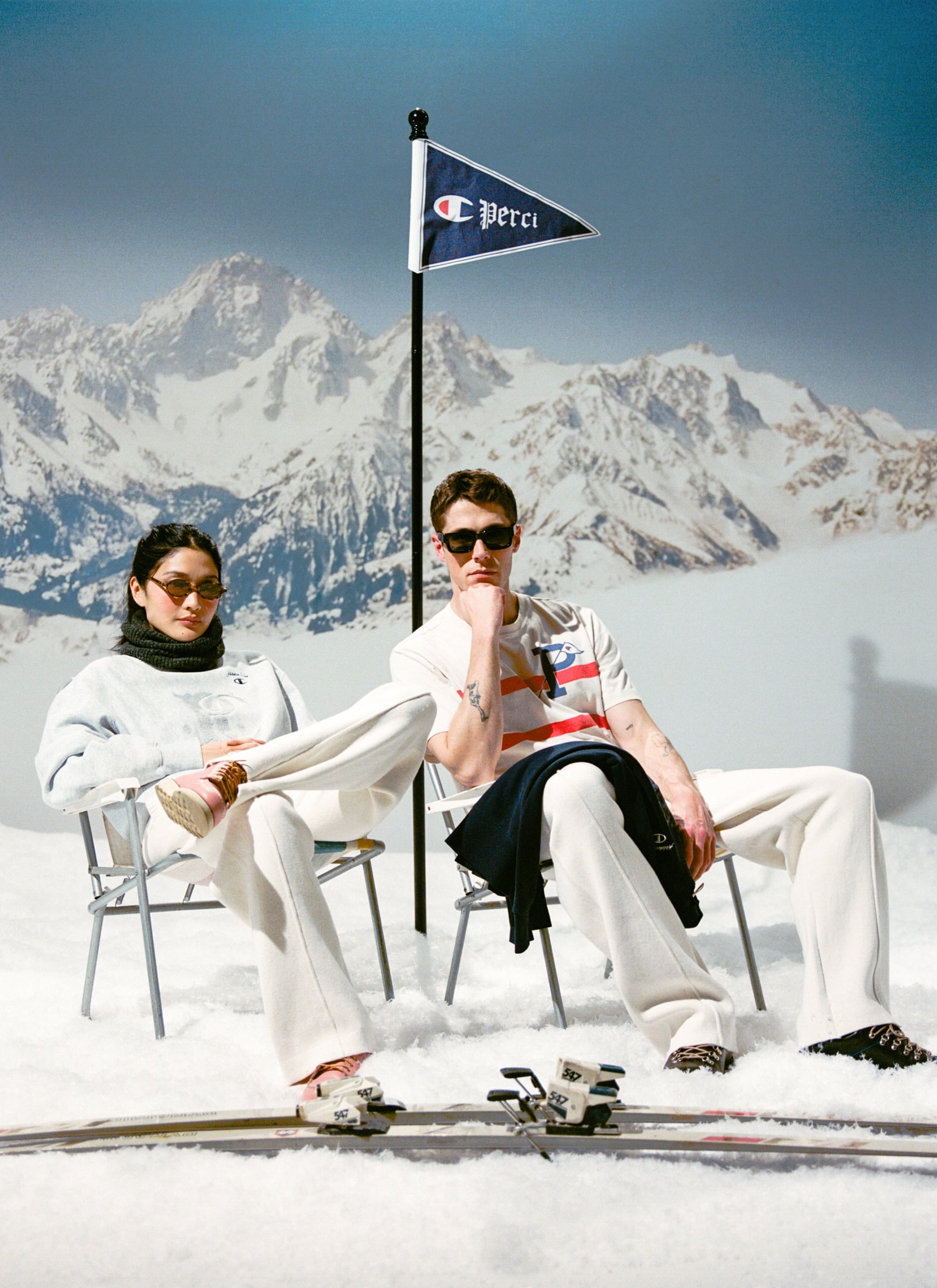 Models showcase the Champion x Percival sweatshirts and t-shirt while relaxing in a vintage-style après-ski scene.