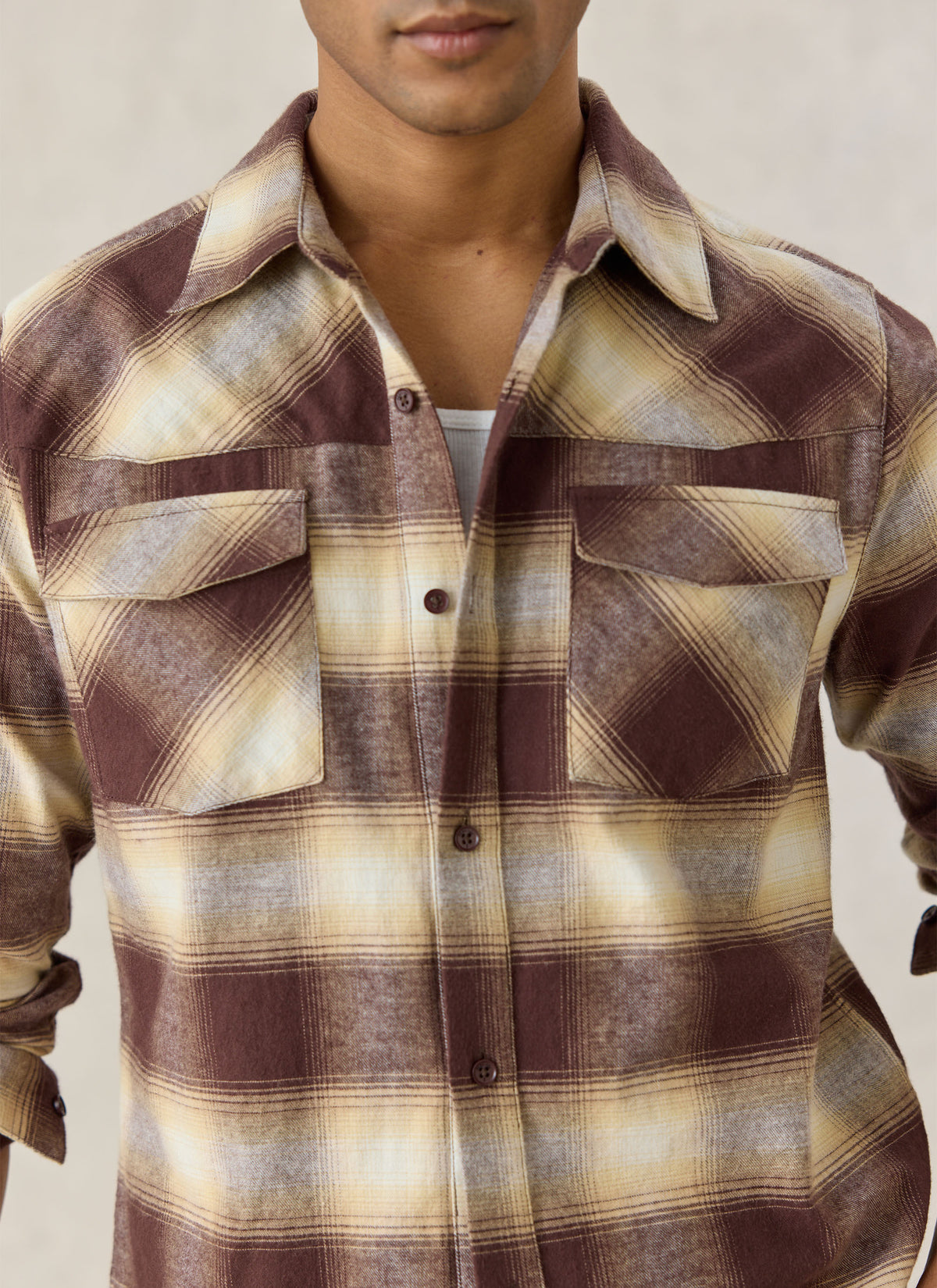 Close-up of a model wearing Percival's brown checked cotton western shirt with dual chest flap pockets.