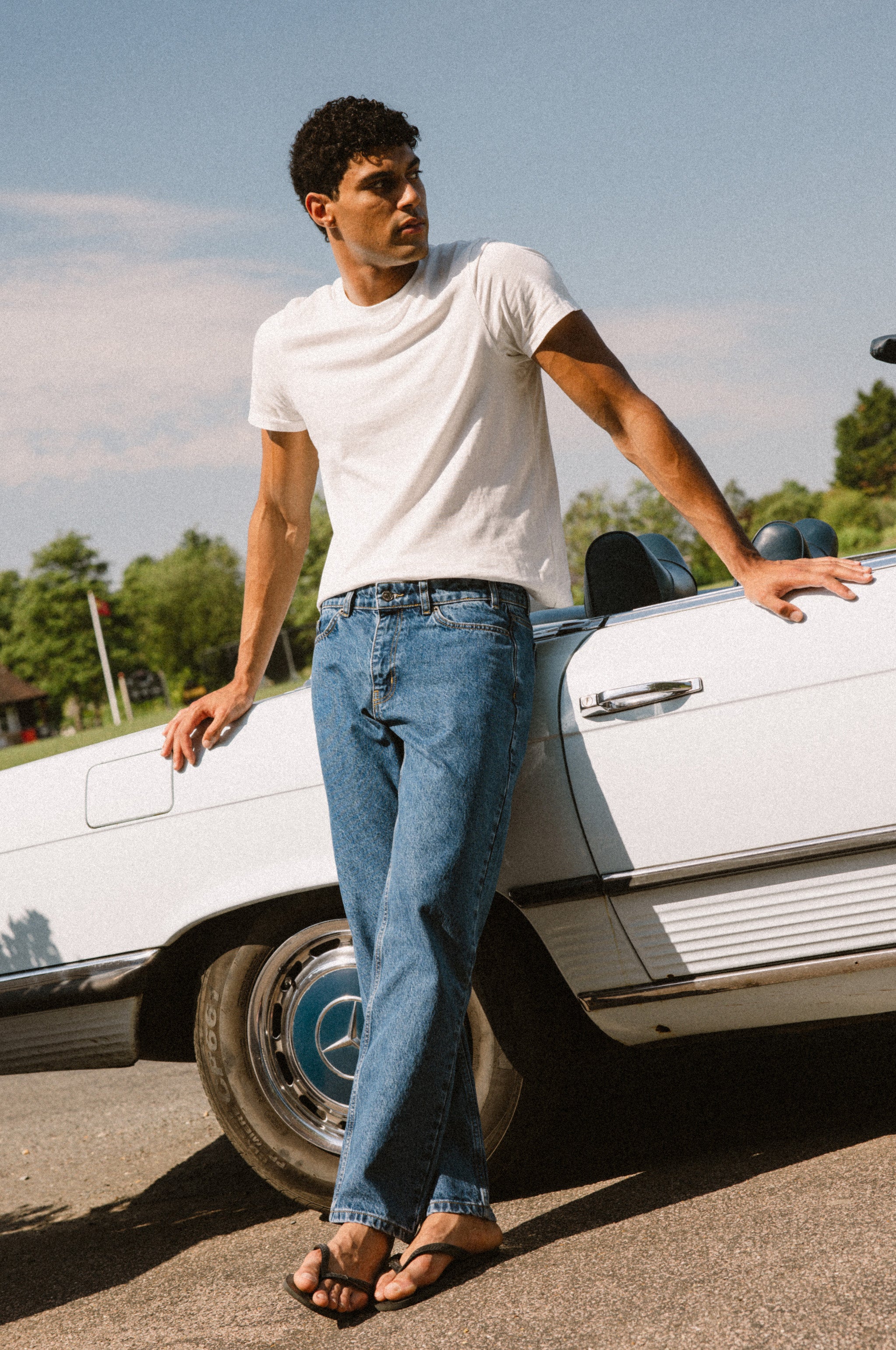 Percival Heritage Denim Jeans in mid wash blue, a structured straight-leg style worn by a model leaning on a vintage car.