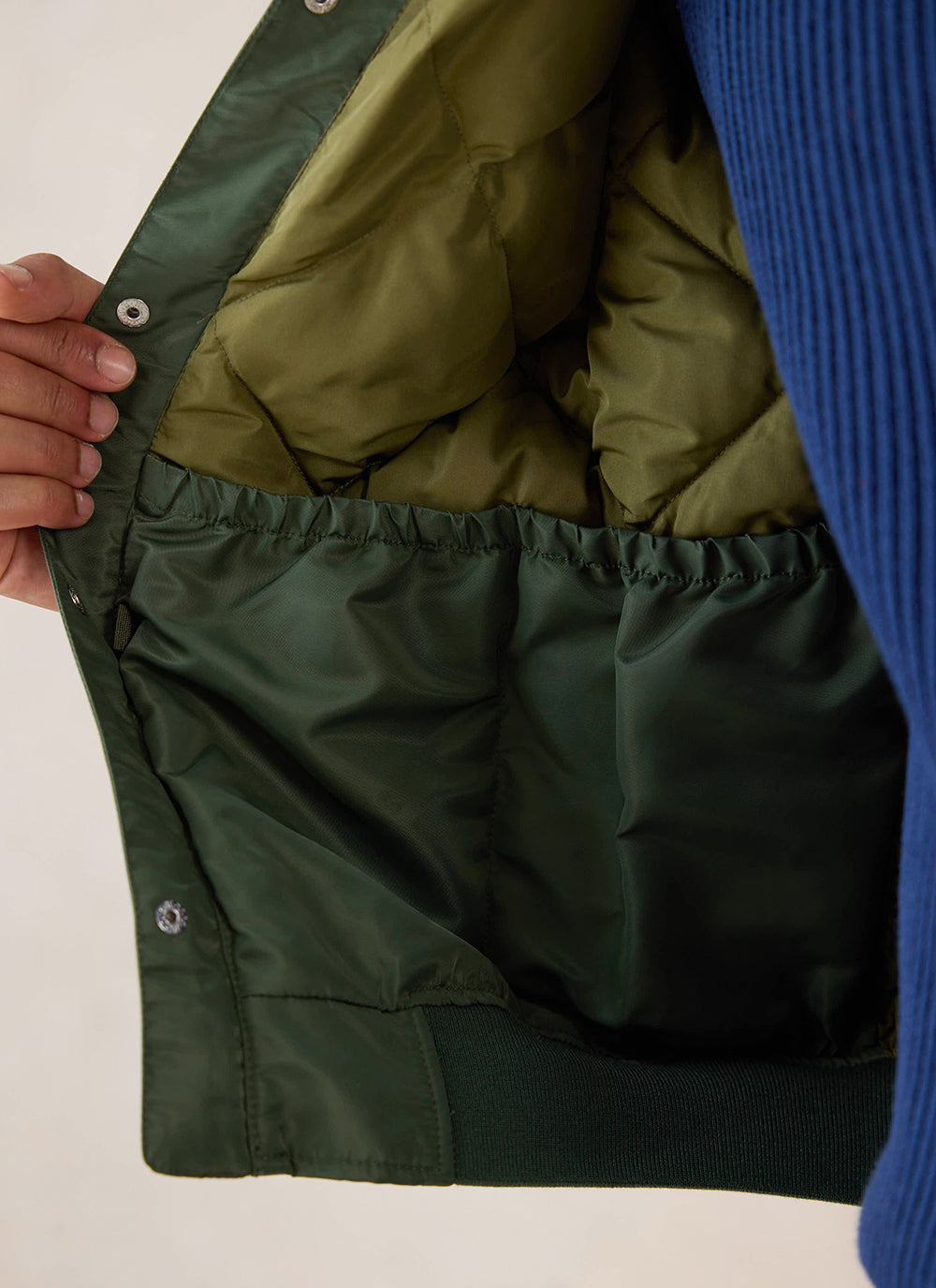 A close-up of the interior quilted lining and pocket of the forest nylon bomber jacket from Percival.