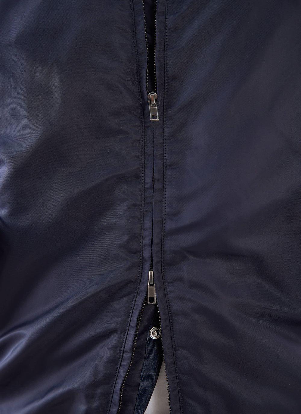 Close-up of the two-way zip fastening on a midnight blue Percival nylon bomber jacket.