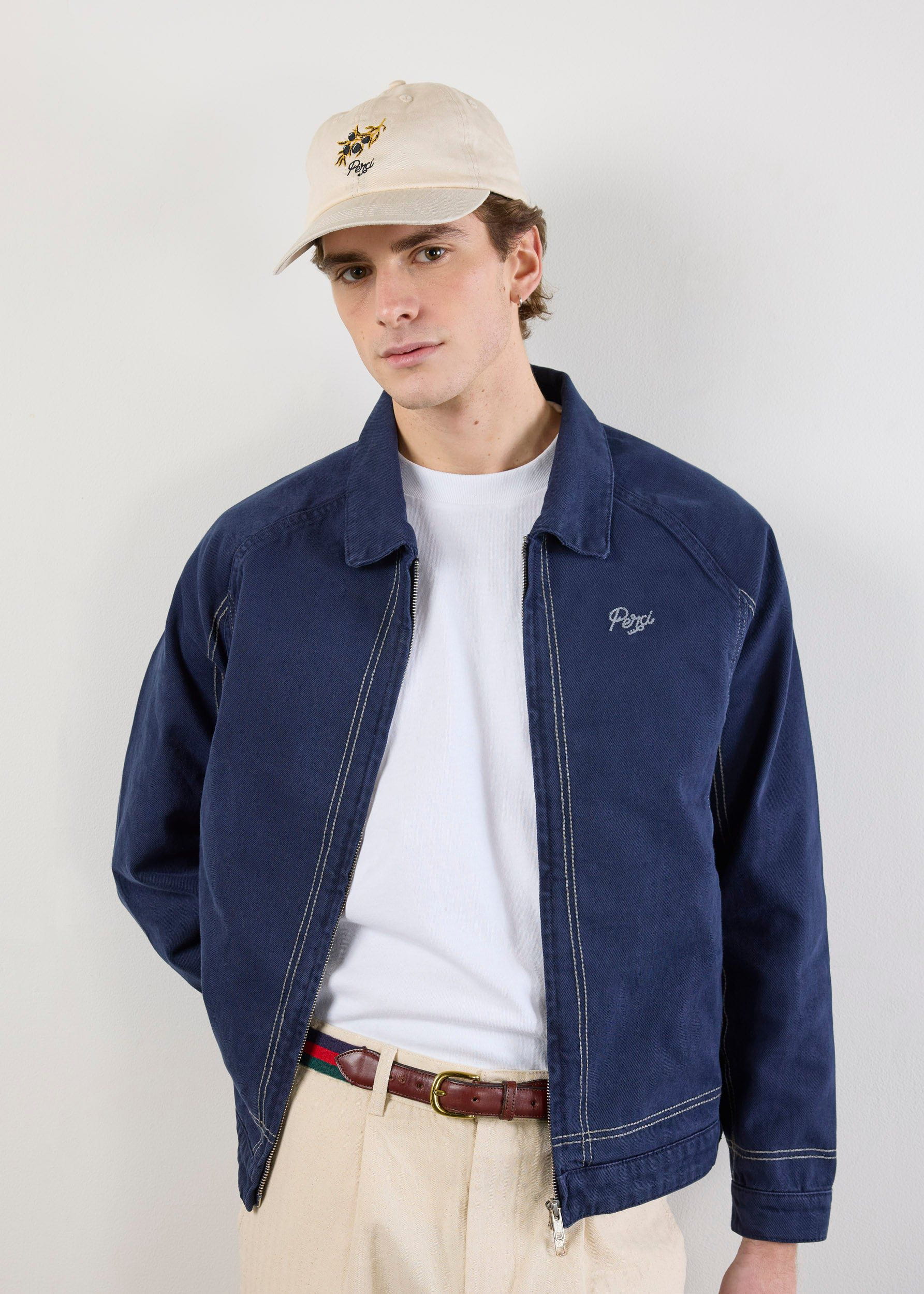 A model wears the Percival Calabria Harrington Jacket in navy, showing its contrast stitching and embroidered chest logo.