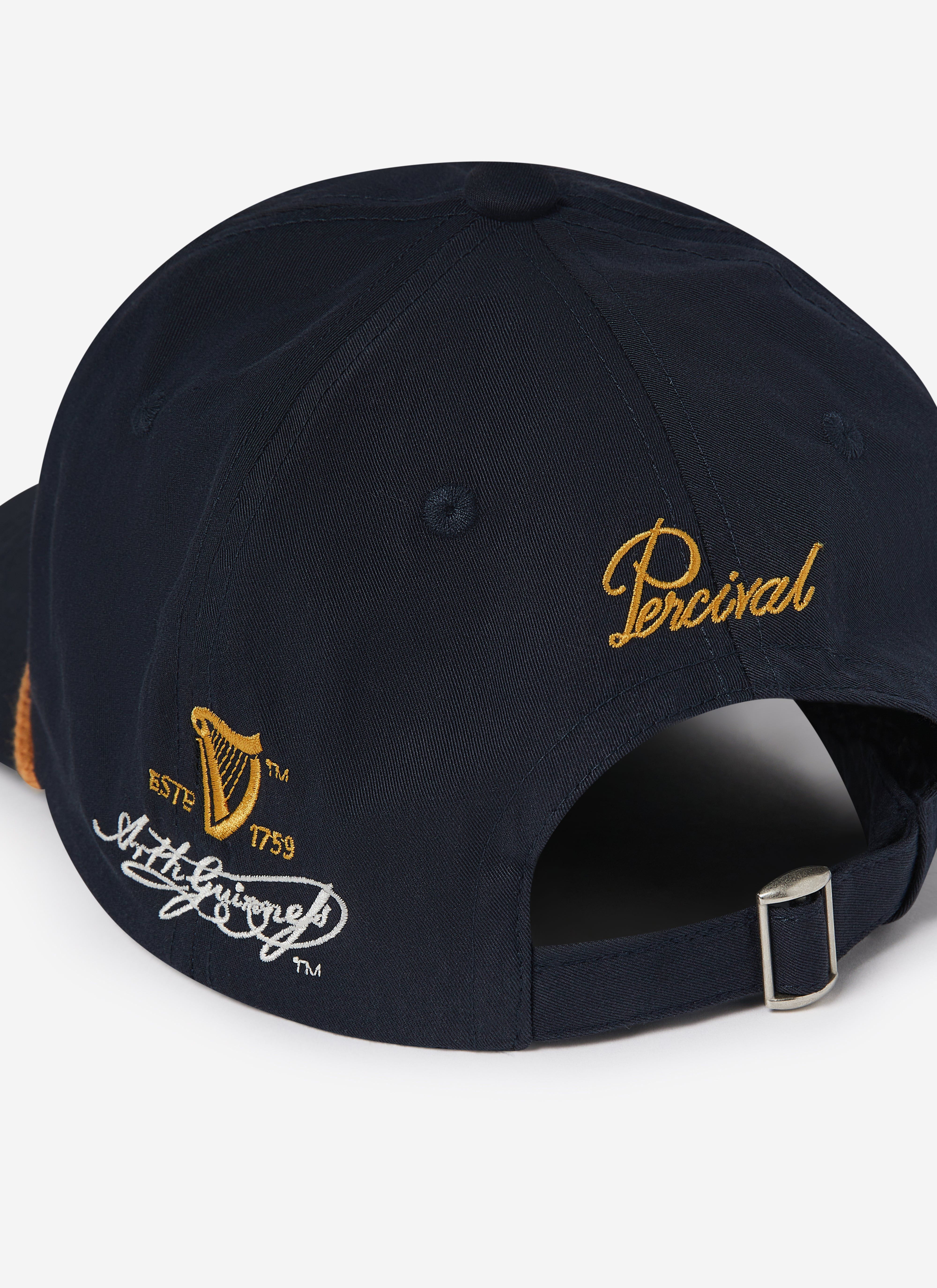 Close-up of the back of the navy Guinness x Percival cap, showing the gold Percival logo and side Guinness embroidery.