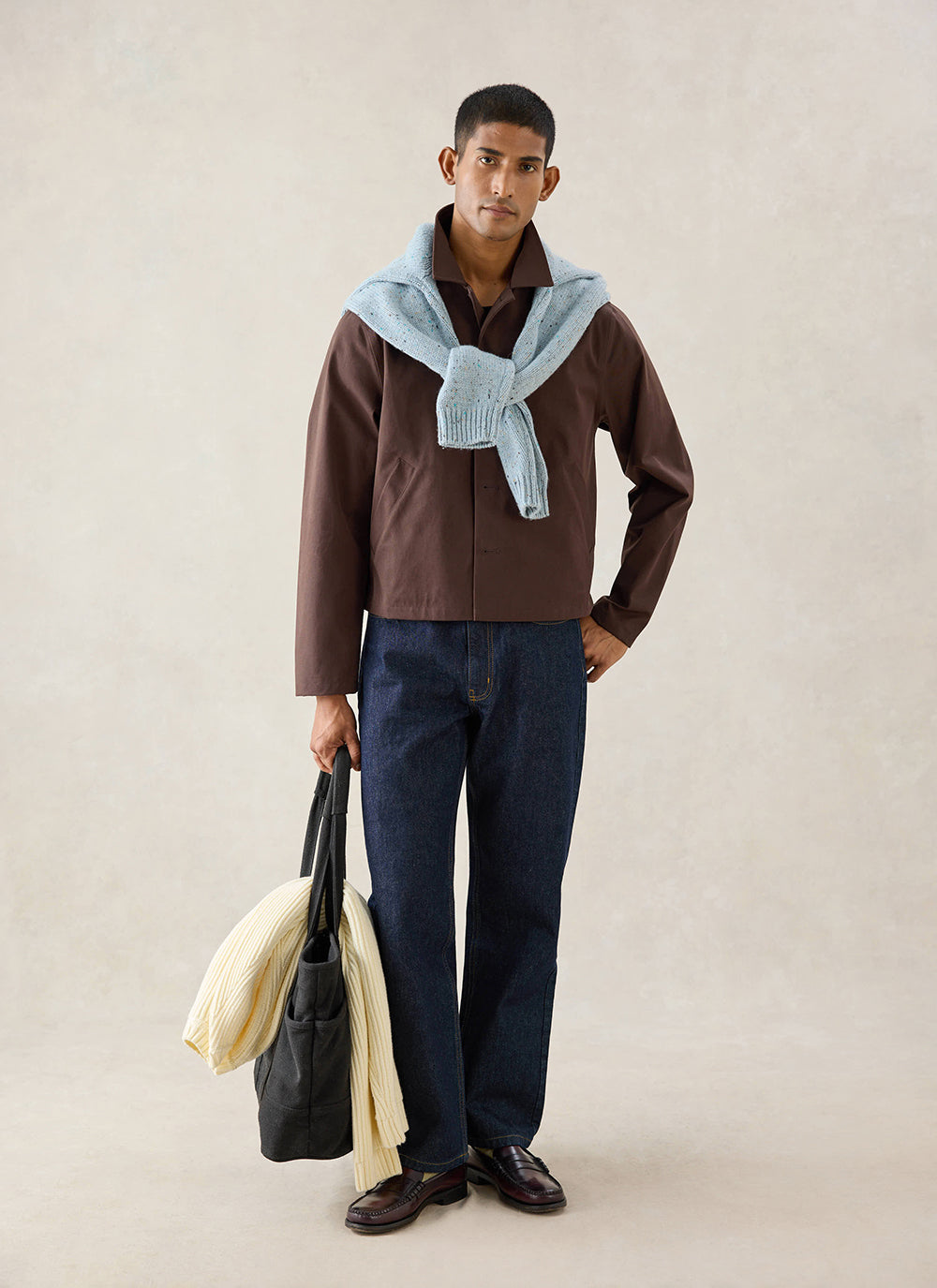 A model wears the espresso Percival Carter Cropped Jacket, styled with dark denim jeans and a light blue jumper.