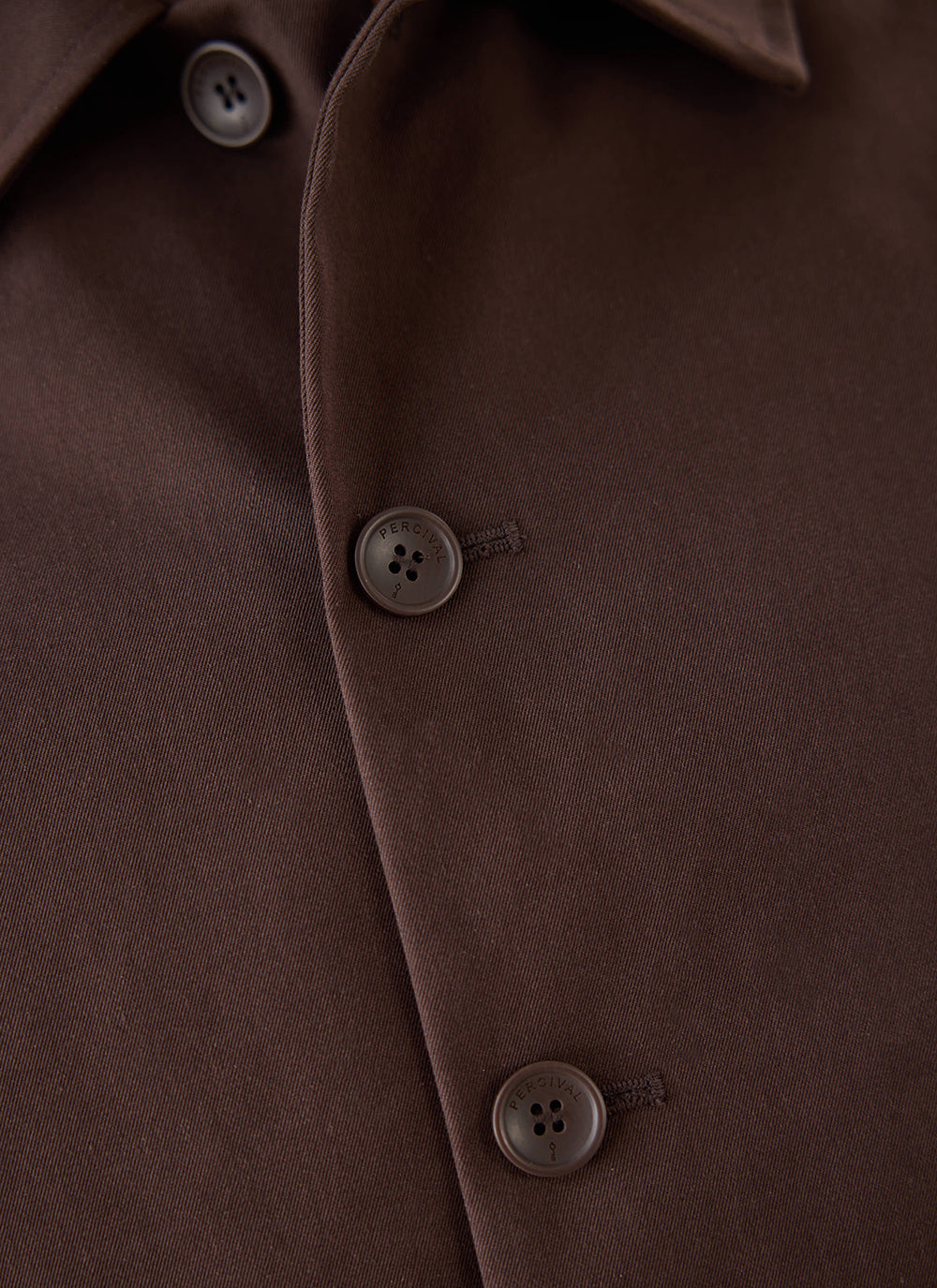 A close-up of the espresso Carter Cropped Trench Coat from Percival, highlighting the button details.