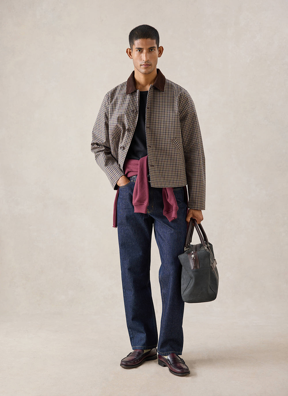A model wears the watcher check Percival Carter Cropped Jacket with a dark bag and denim jeans in a studio shot.