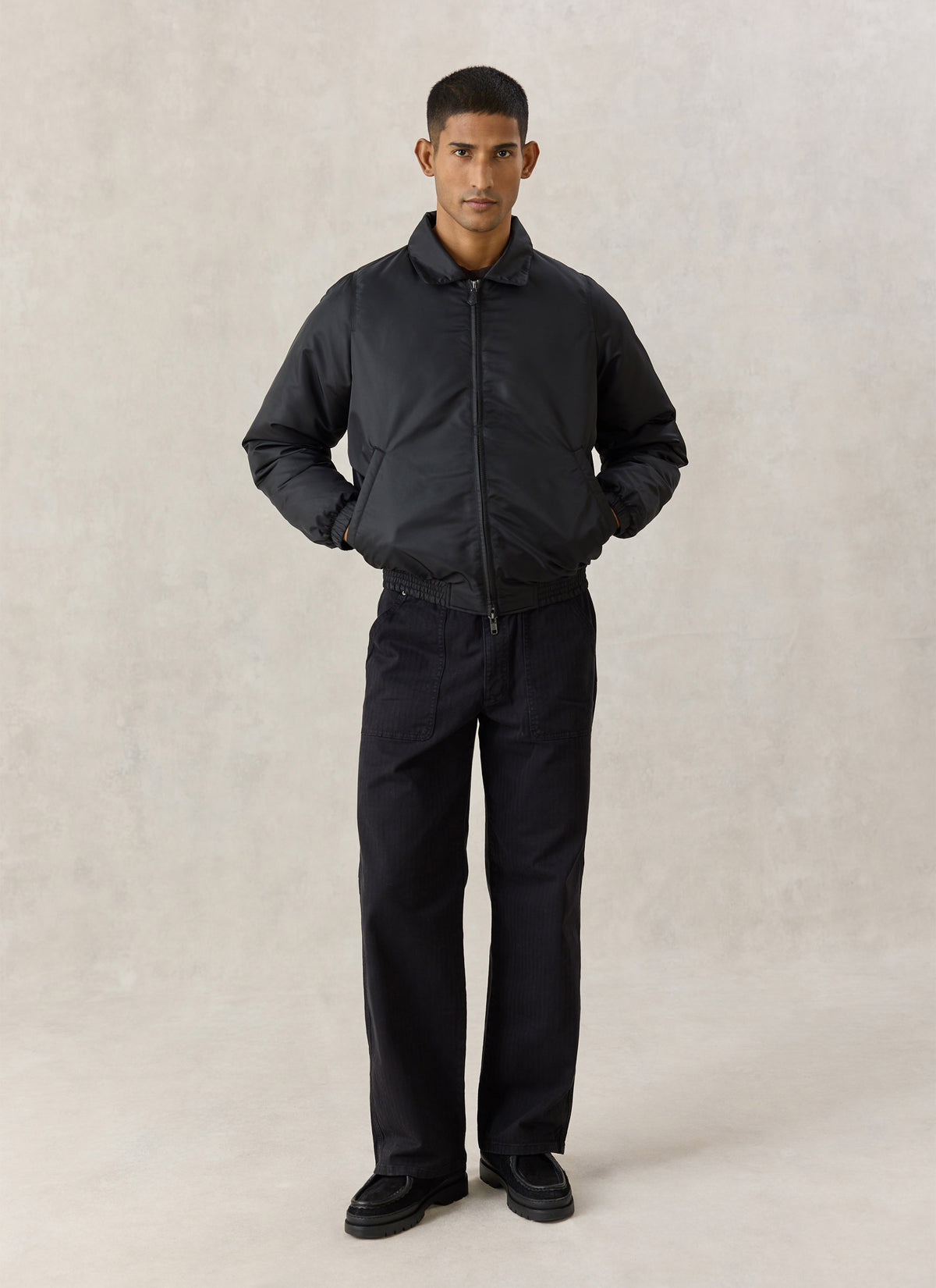 A model wearing the Percival black nylon collared bomber jacket with dark trousers against a neutral background.