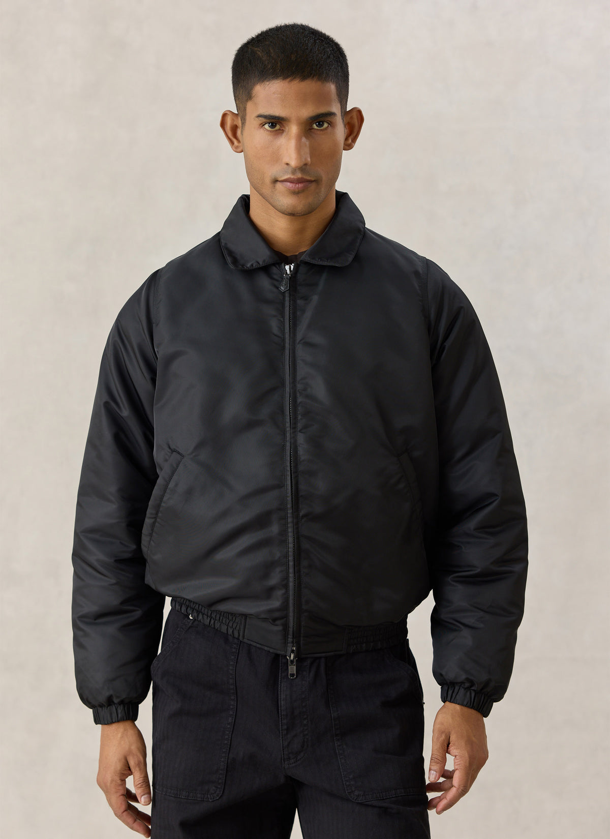 A model wearing the black Percival nylon collared bomber jacket, showing the front view, zip, and smart collar.