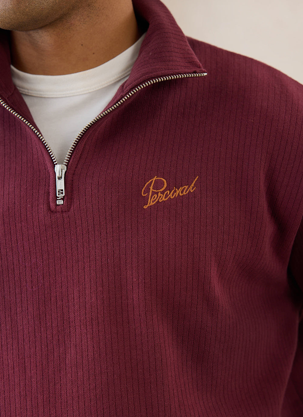Close-up of a burgundy Percival Conrad 1/4 zip jumper in cotton, showing the ribbed texture and zipper detail.
