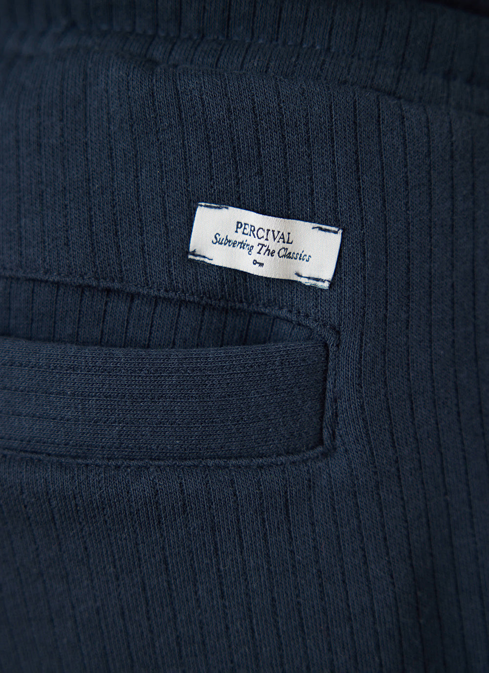 Close-up of the navy Percival Conrad trackpants showing the back pocket and branded label detail.