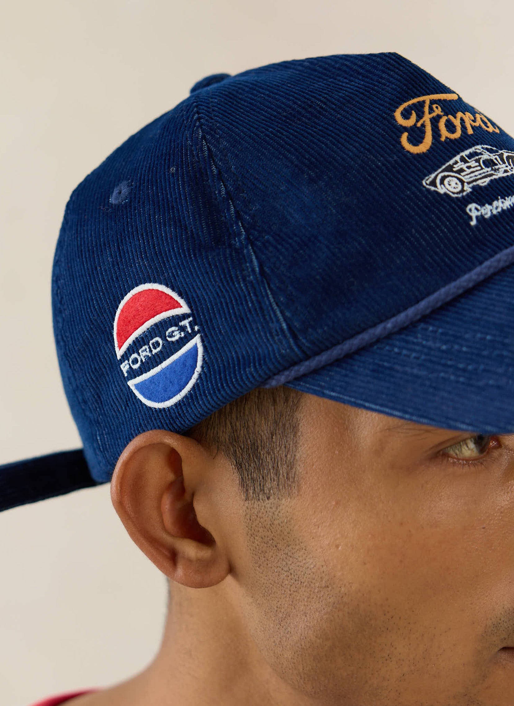 Navy cord soft trucker cap by Percival with Ford G.T. embroidery, side badges, and a contrast rope trim detail.