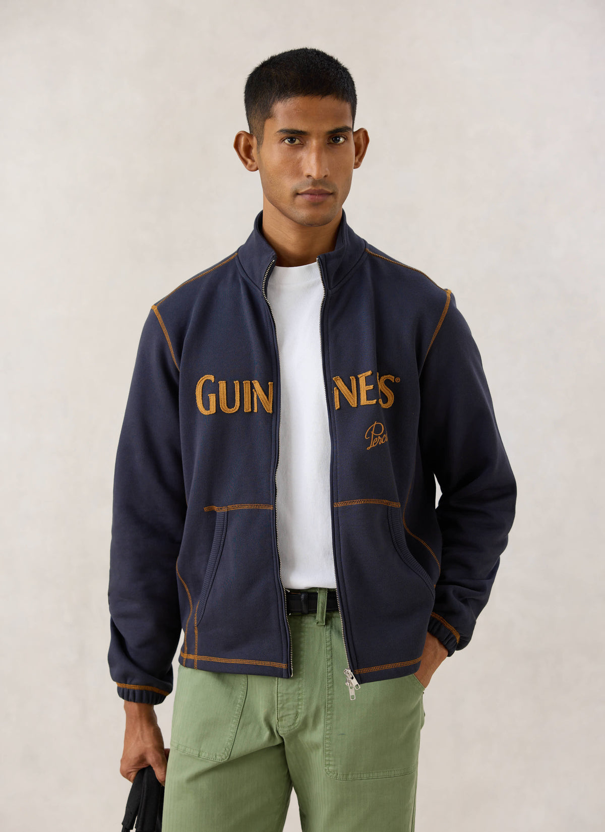 Model wearing the navy blue Guinness x Percival zip sweatshirt with appliqué branding and contrast stitching.