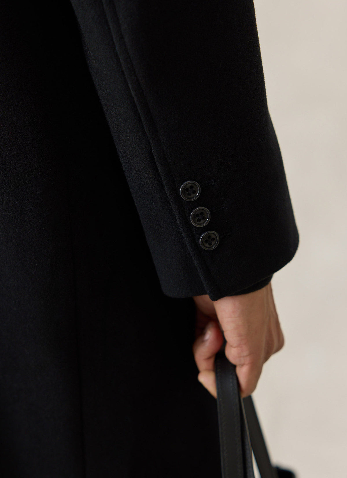 Close-up of the sleeve cuff on the black Percival wool blend double-breasted overcoat, highlighting the three buttons.