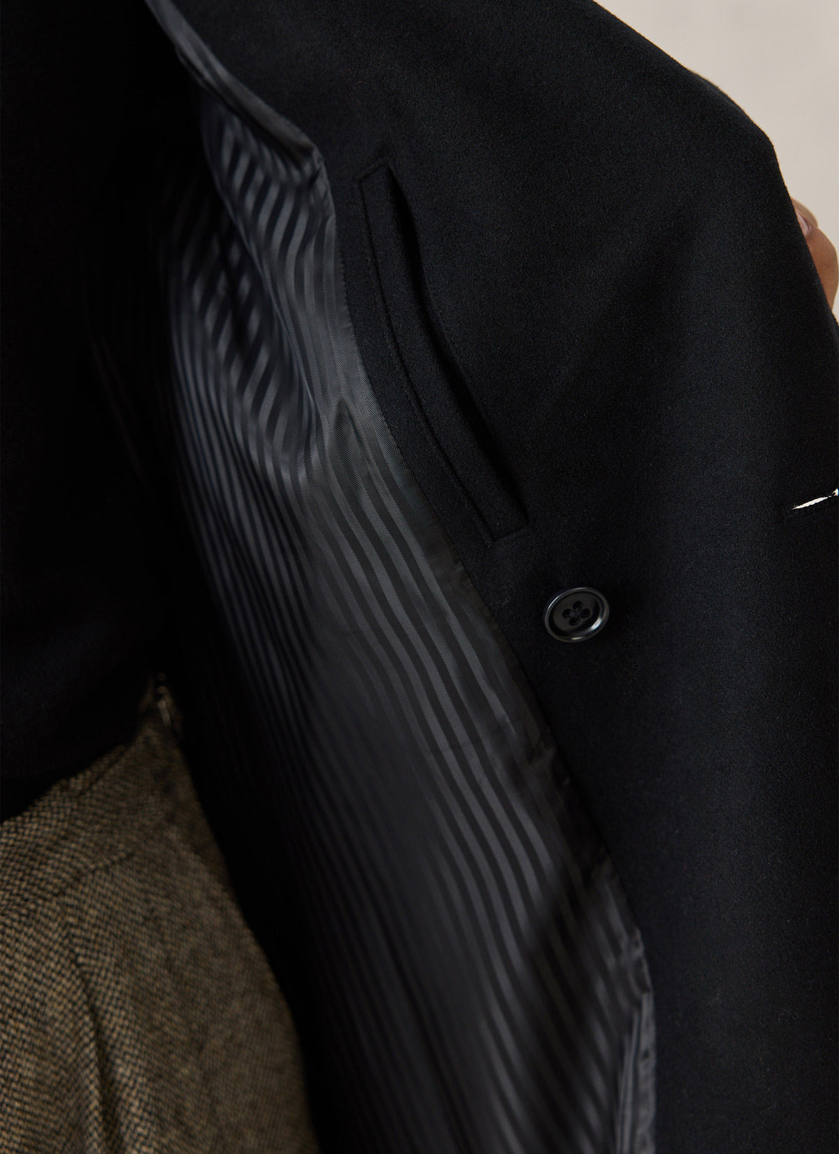 A close-up of the Percival wool blend double-breasted overcoat highlighting the inner lining, pocket detail, and button.
