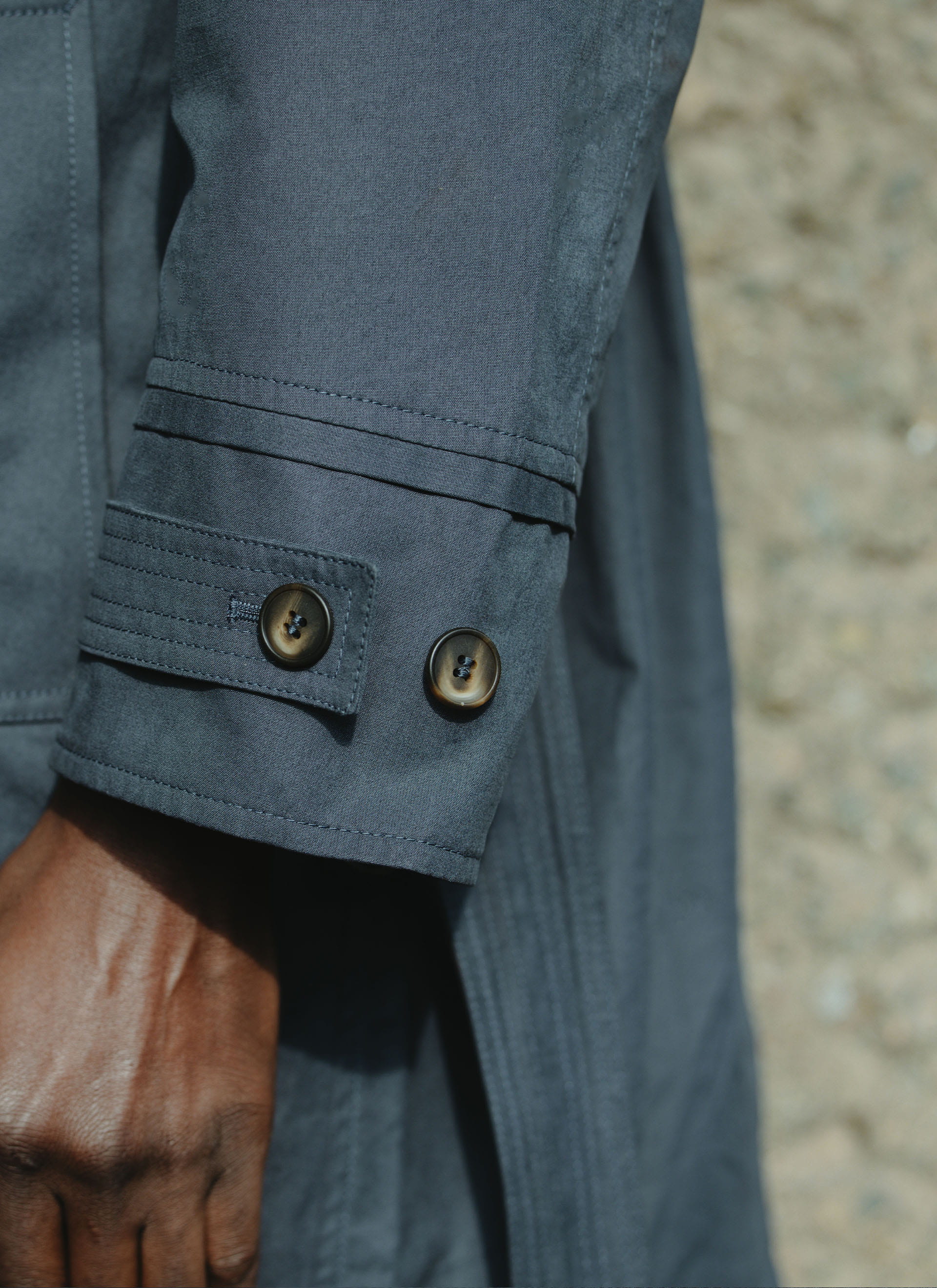 Close-up of the navy peached cotton sleeve cuff and buttons on the Front Office x Percival Mac Coat.