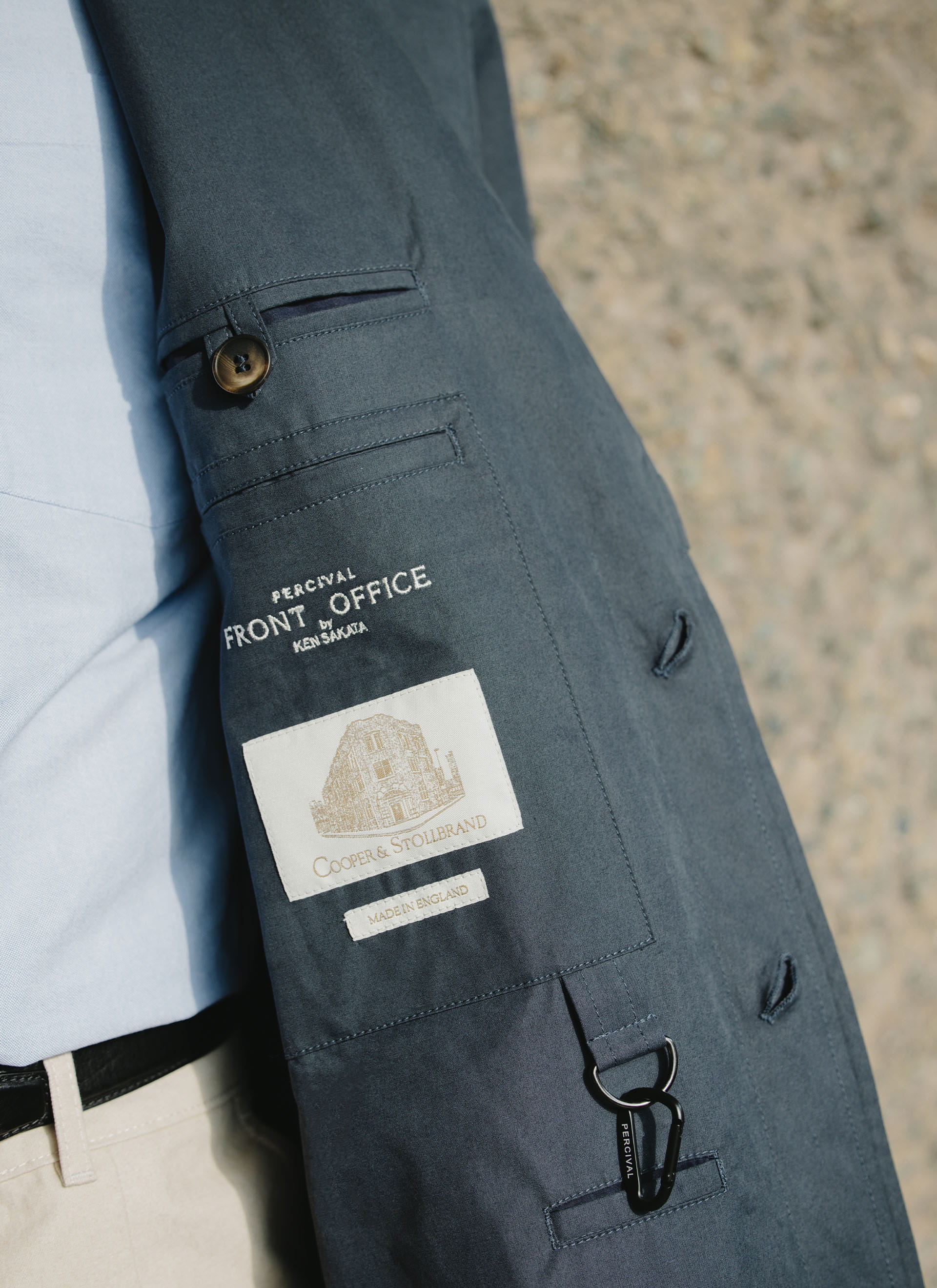 Detail of the navy Percival x Front Office Mac Coat, showing the internal labels, carabiner, and peached cotton finish.