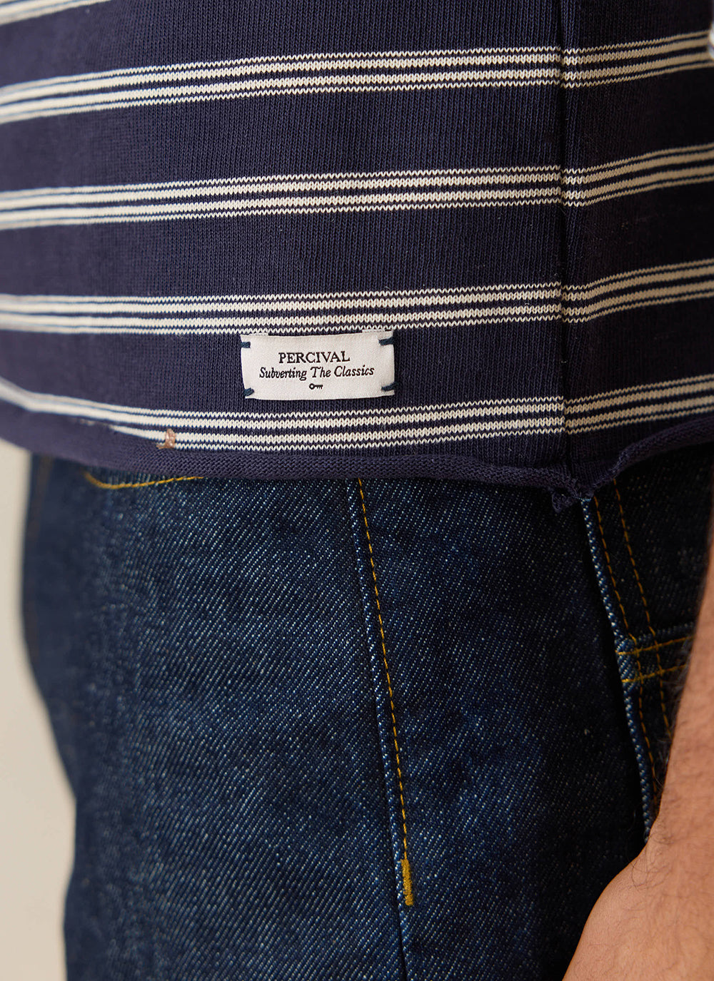 A close-up of the Percival navy stripe Breton t-shirt, showing the brand label near the raw hem.