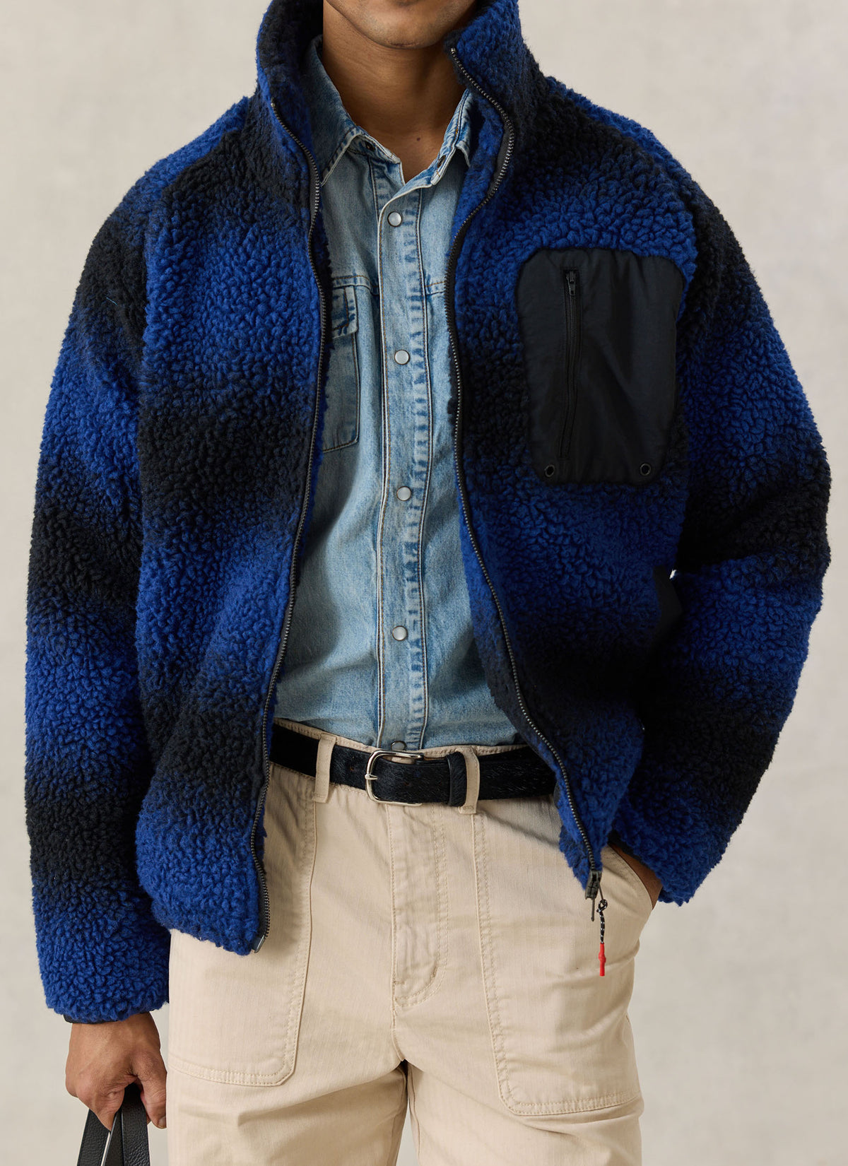 A model wearing the Percival ombre blue wool fleece jacket with a stand collar and chest pocket over a denim shirt.