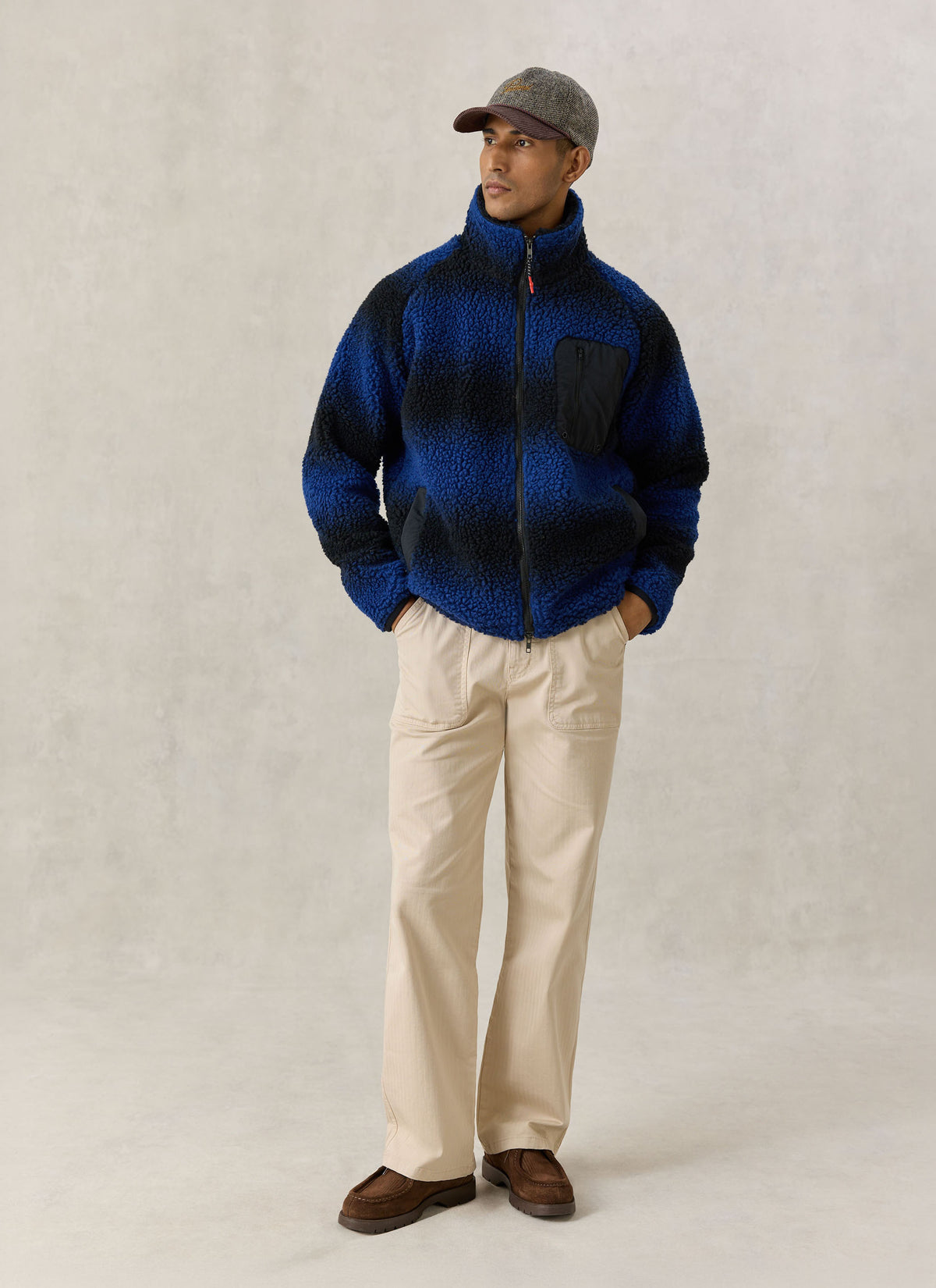 A model wearing the Percival ombre blue wool-blend fleece jacket with a stand collar and beige trousers.