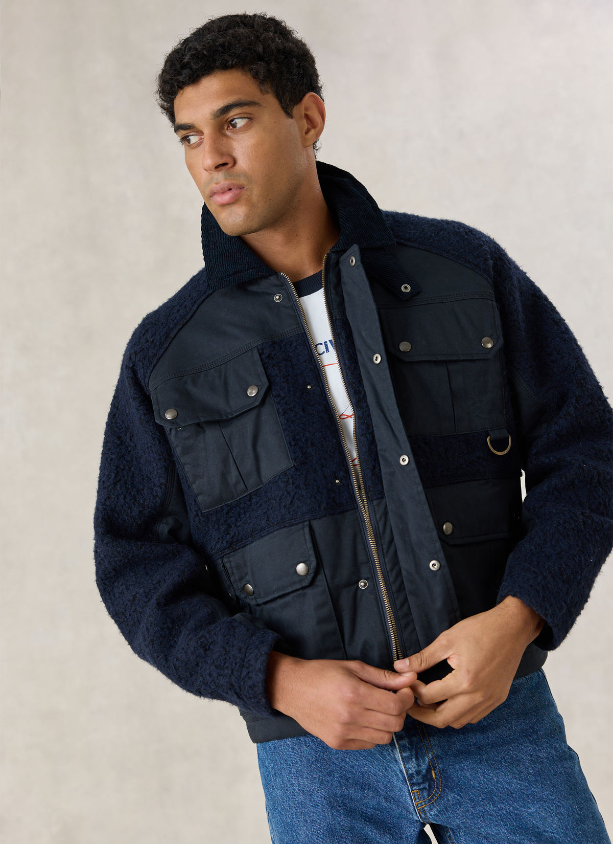 A model wearing the Percival navy blue Fletcher utility fleece and wax jacket with a cord collar and front pockets.