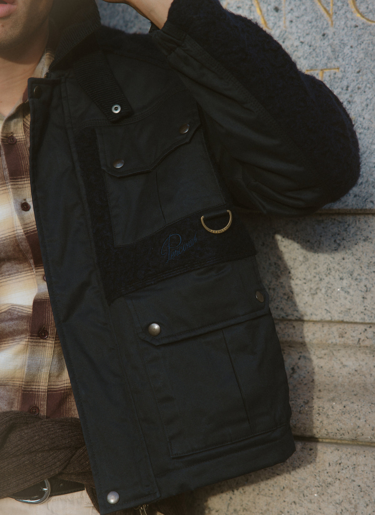 Close-up of the Percival navy Fletcher utility fleece and wax jacket, showcasing flap pockets and a D-ring detail.