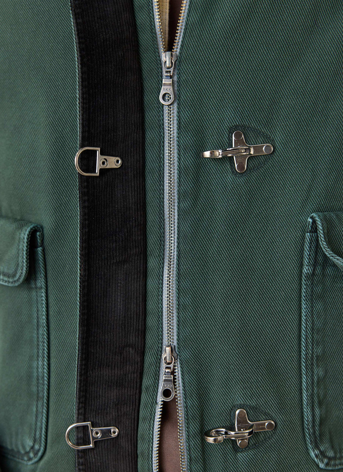Close-up of the forest green Percival Fontane cotton jacket, highlighting metal fireman clasps and zip front.