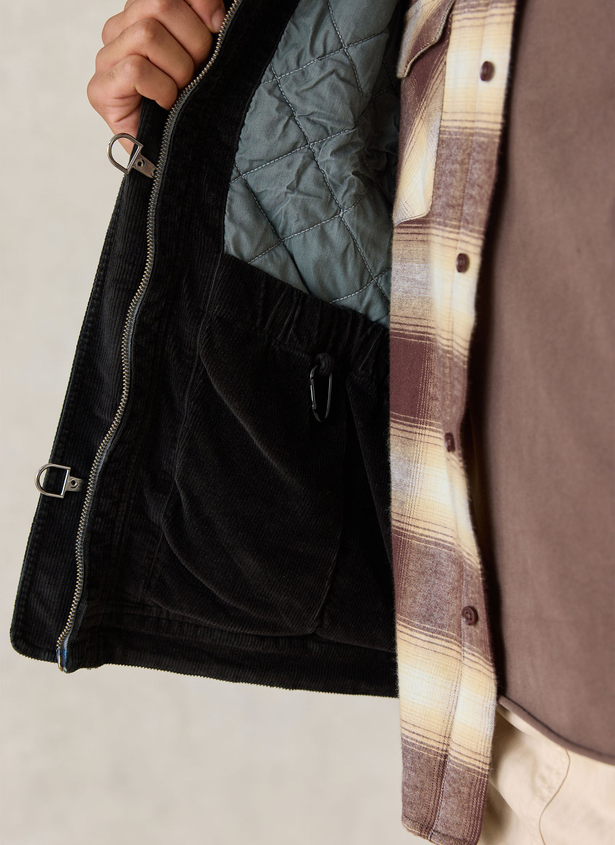 A close-up of the Percival forest green cotton jacket showing the quilted interior lining, zipper, and fireman clasps.