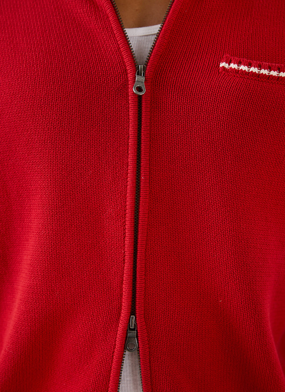 Close-up of the red Percival Gardner dense knitted cotton zip cardigan, showing the two-way zip and chest welt pocket.