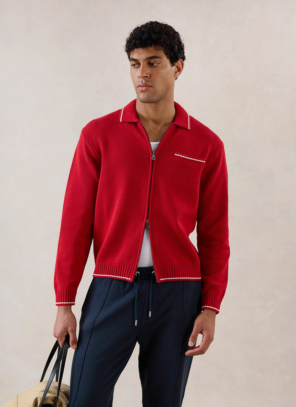 A model wearing a red Percival zip cardigan in cotton with contrast stitch detailing, styled with dark trousers.