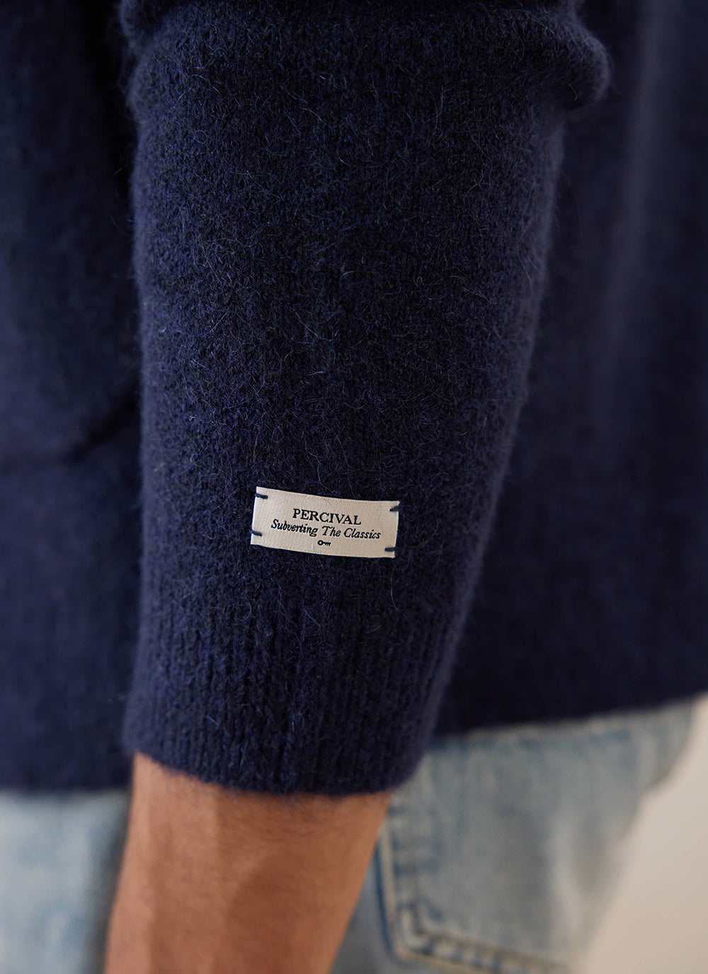 A close-up of the navy Gibson cardigan from Percival, showing the branded label on the sleeve.