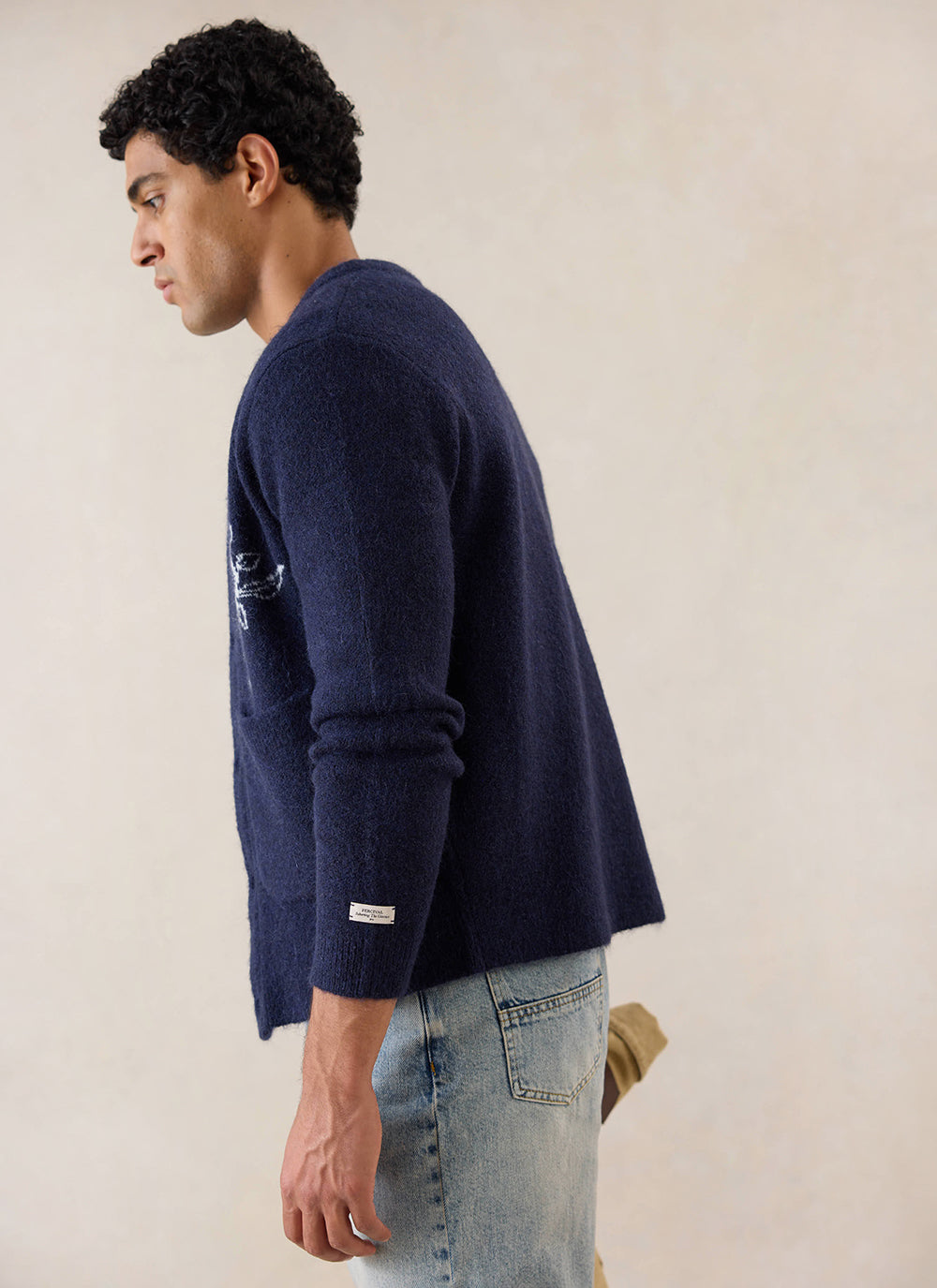 A side profile shot of a model wearing the navy Percival Gibson Boxy Jacquard Cardigan, styled with light wash jeans.