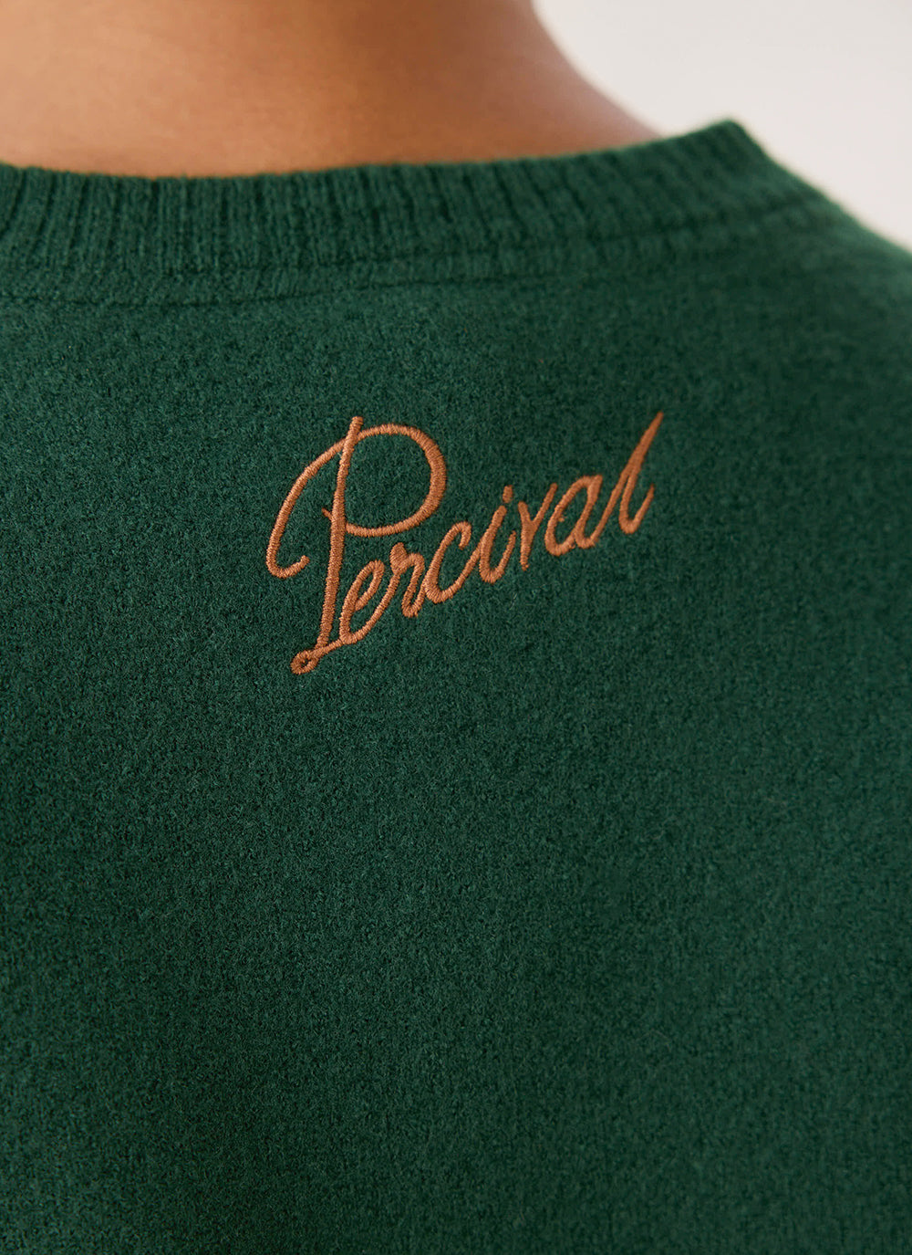 Close-up of the back neck on the forest green Guinness x Percival wool jumper, showing the contrast script embroidery.