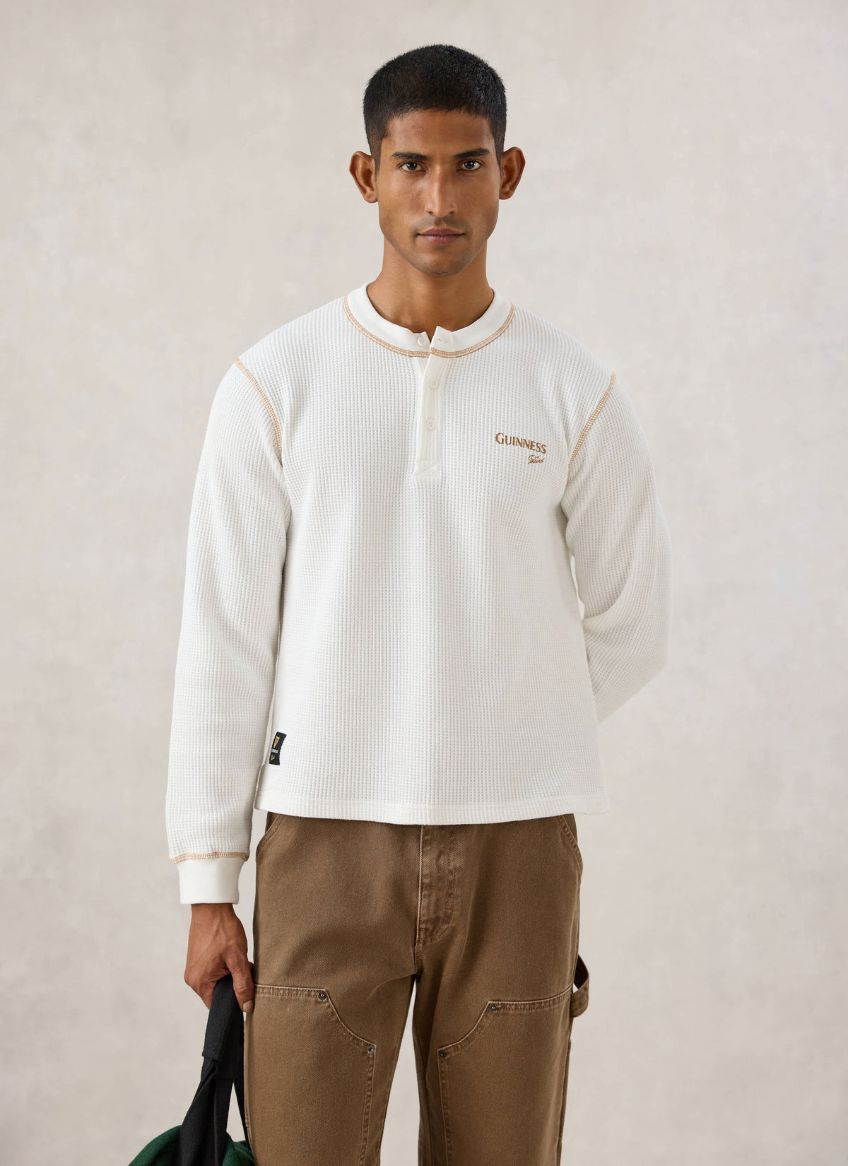 Model wearing the cream Guinness x Percival waffle henley with contrast stitching and chest logo.