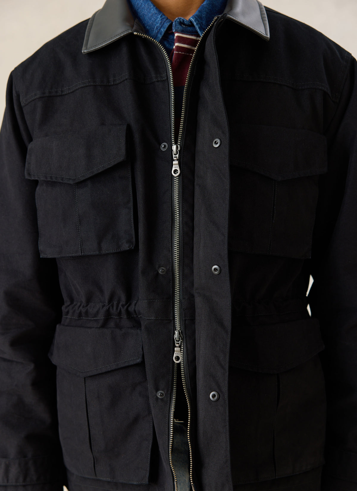 Close-up of the black Percival Harris Field Jacket showing front flap pockets, zip closure, and contrasting collar.