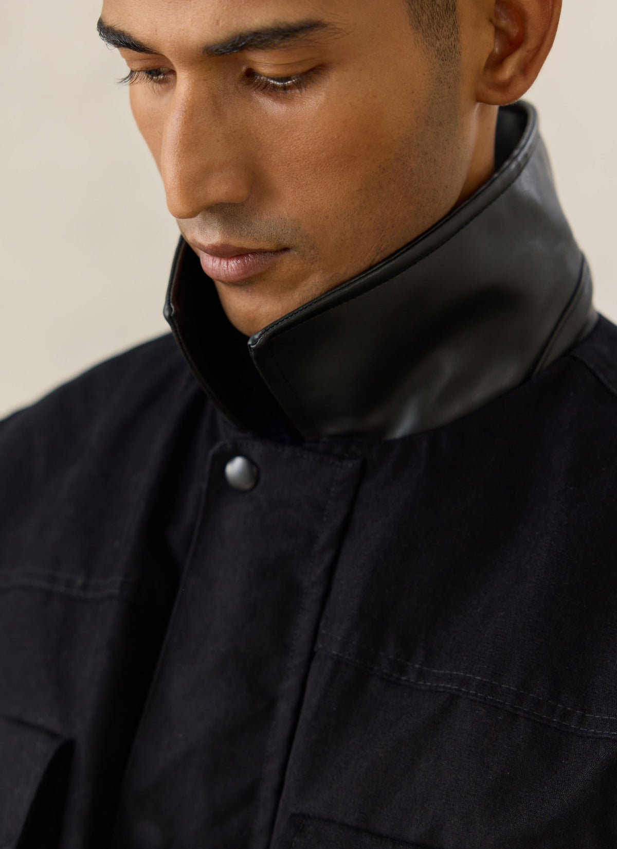 A close-up of a model wearing the black Percival Harris Field Jacket, highlighting the collar and placket.