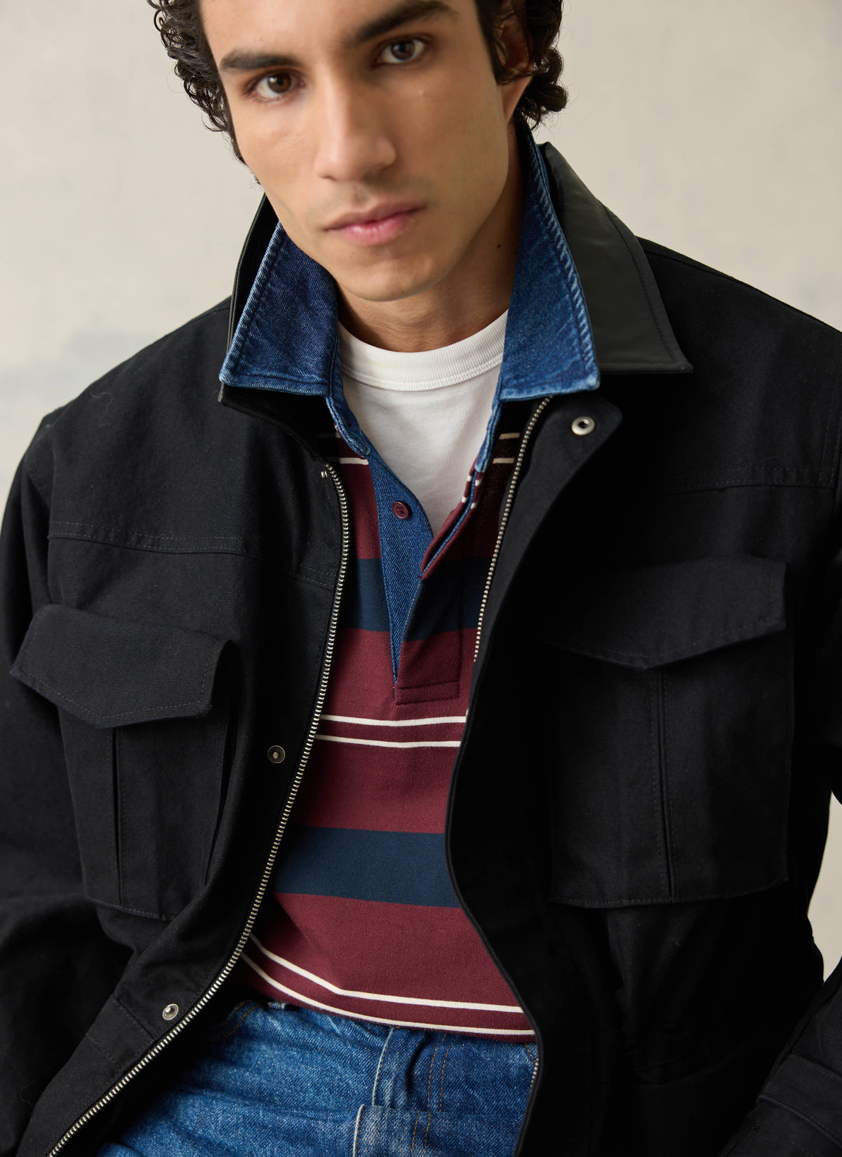 A model wearing the burgundy striped Percival rugby polo shirt with a denim collar layered under a black jacket.