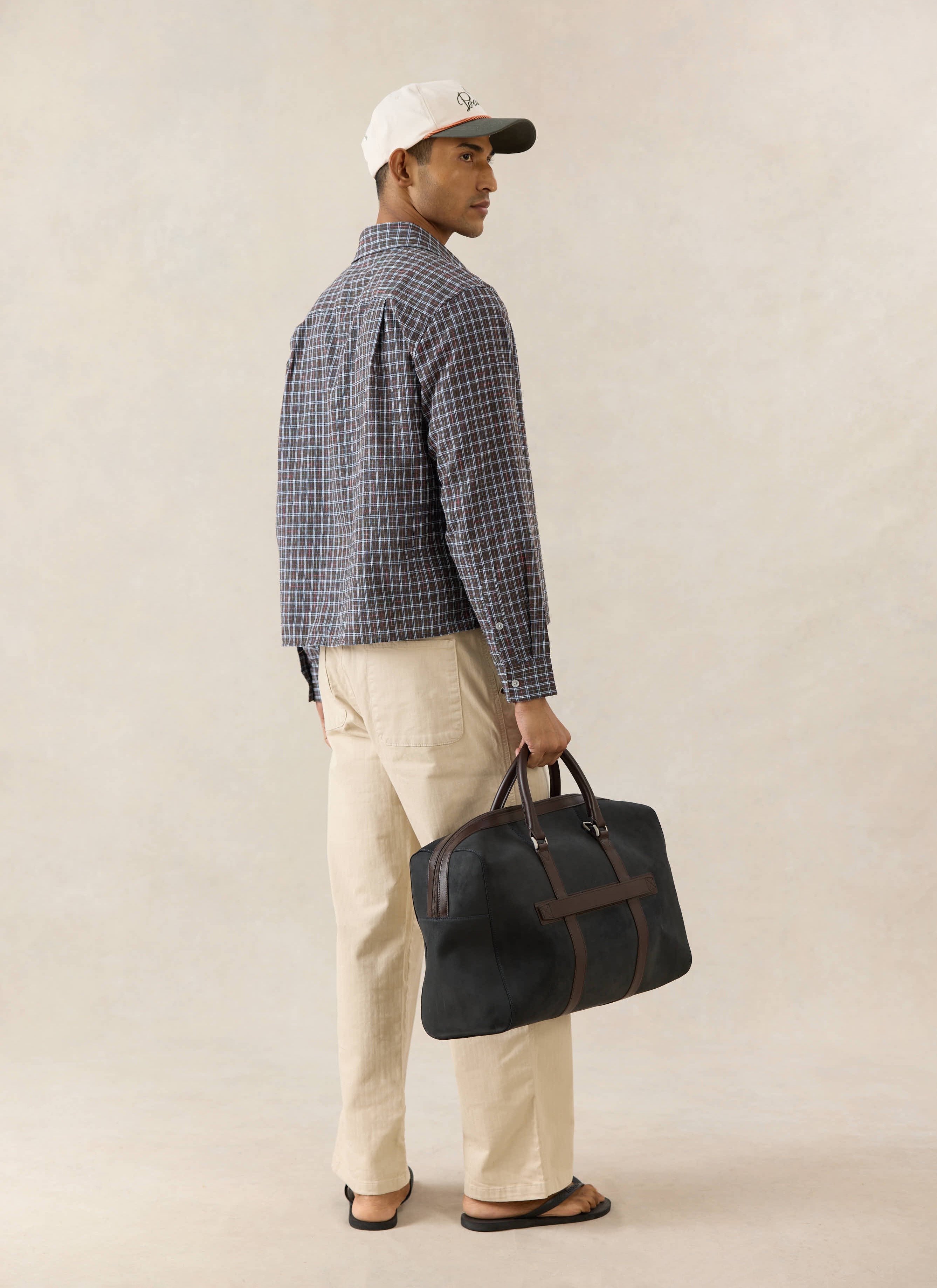 Percival Hinsley brown micro check boxy cotton shirt, viewed from the back on a model with beige trousers and a bag.