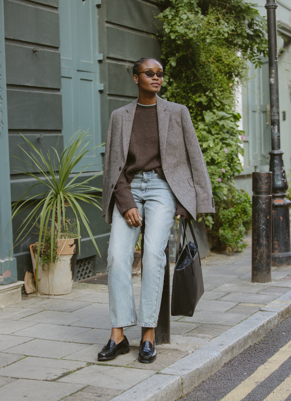 A model wearing the brown Hurst ribbed wool jumper under a grey blazer, paired with light-wash jeans and loafers outdoors.