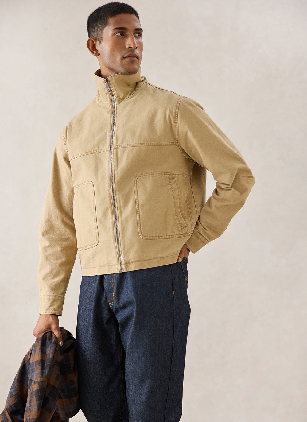 A model wears the cream Percival Jackson Boxy Harrington Jacket, styled with dark denim jeans in a studio setting.