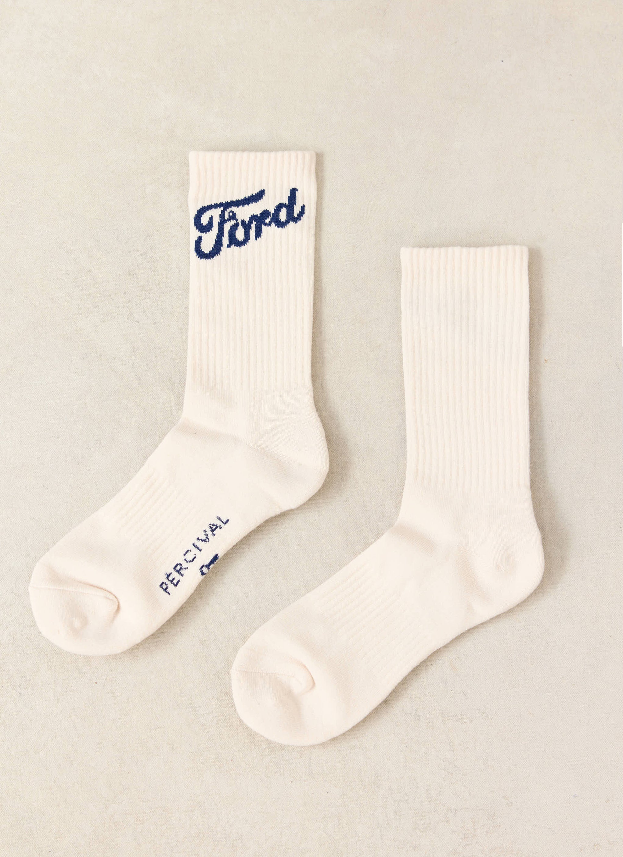 Cream Ford x Percival jacquard socks in a ribbed cotton blend, featuring a blue script logo and Percival branding.