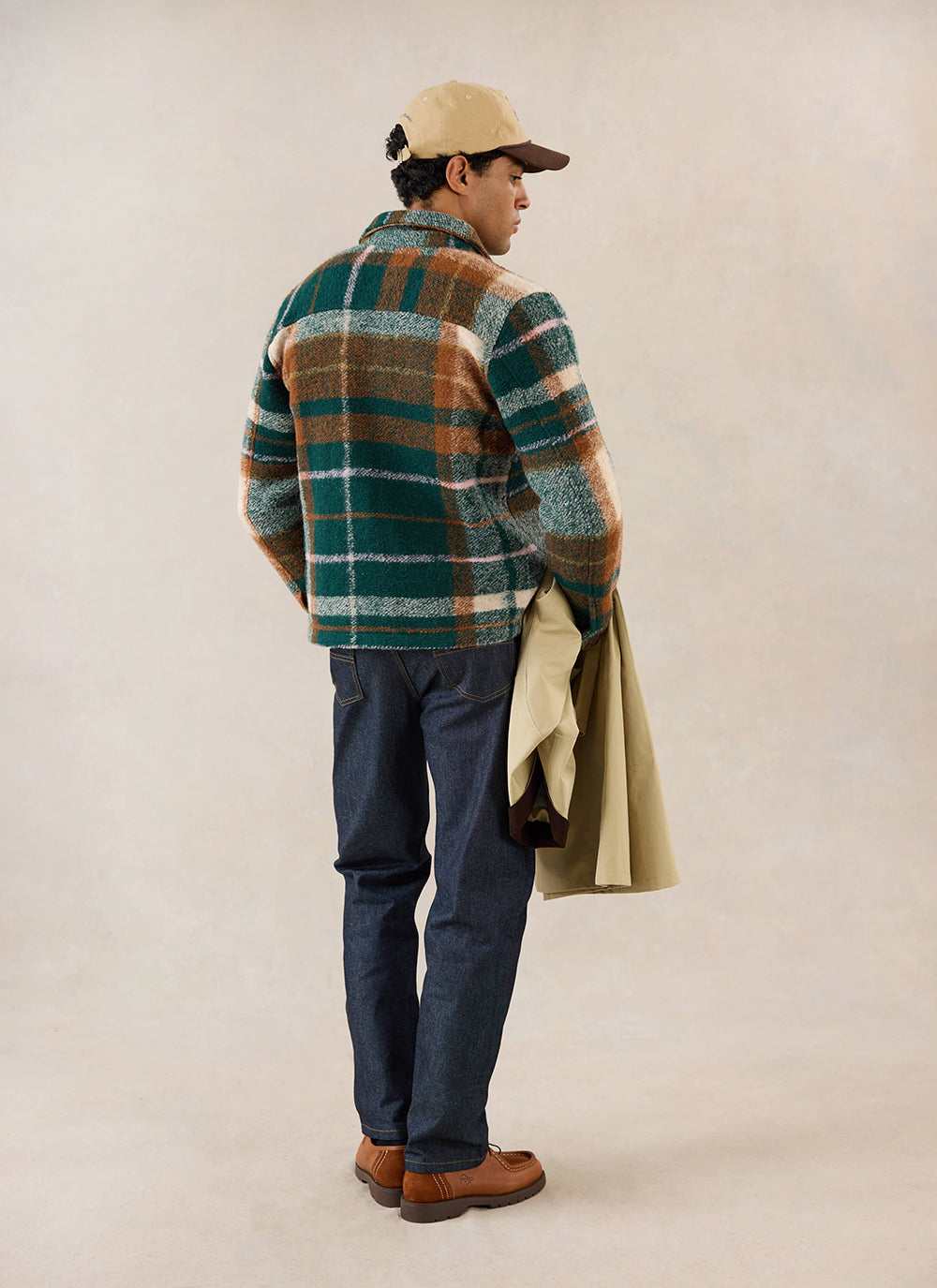 A model from behind wears the multi check Percival Knowles overshirt, styled with blue jeans and a cap.