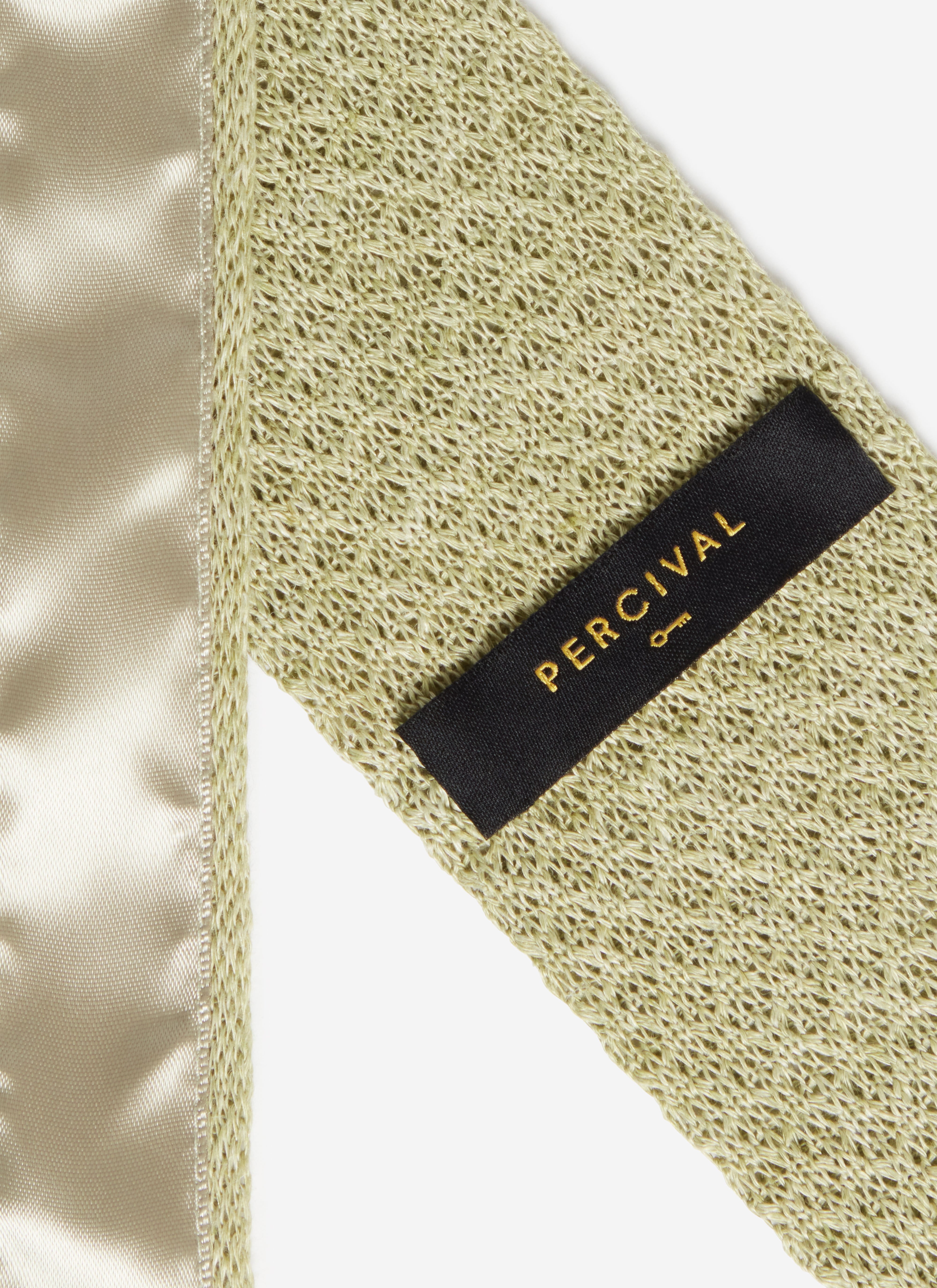 A close-up of the Percival brand label on the reverse of the Linen Tie in Forest Marl, highlighting the woven texture.