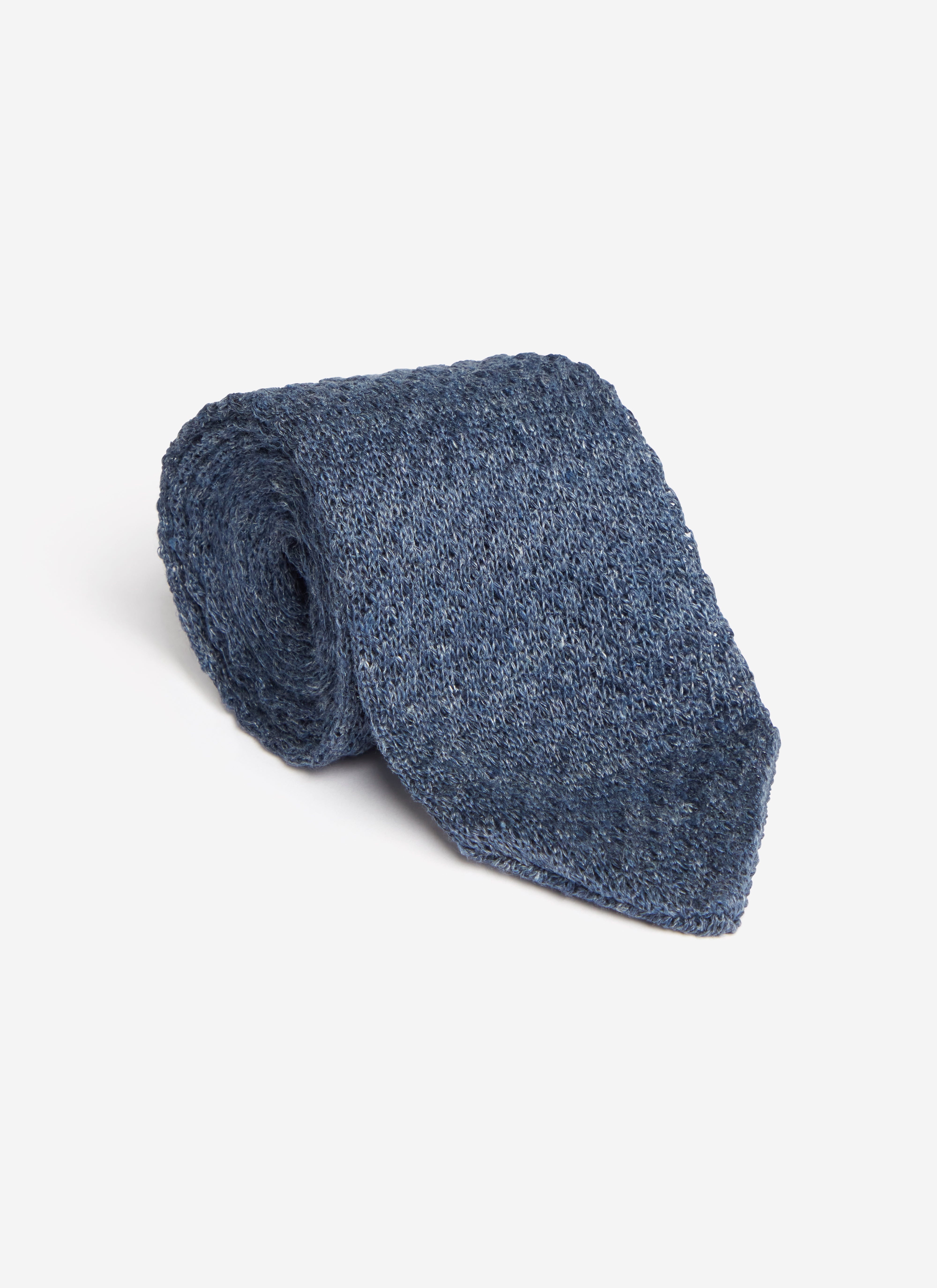 A studio shot of the Percival Linen Tie in navy marl, rolled up to show the texture of the 100% linen fabric.