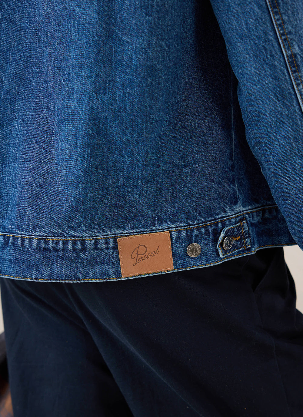Close-up of the leather patch and buttons on the mid-wash blue Percival Mackey Zip Jacket.