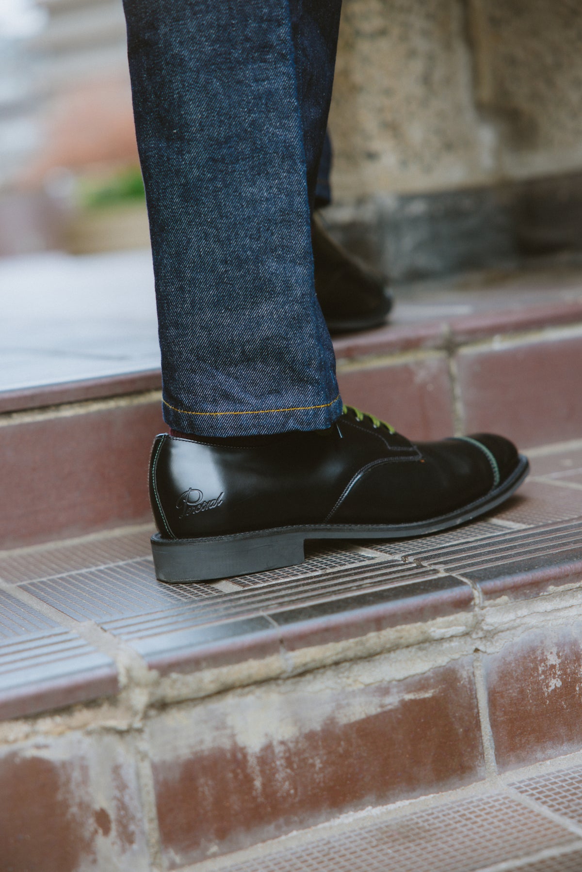 Black leather Derby shoes by Percival styled with denim trousers, showing the heel branding and stitched details on steps.