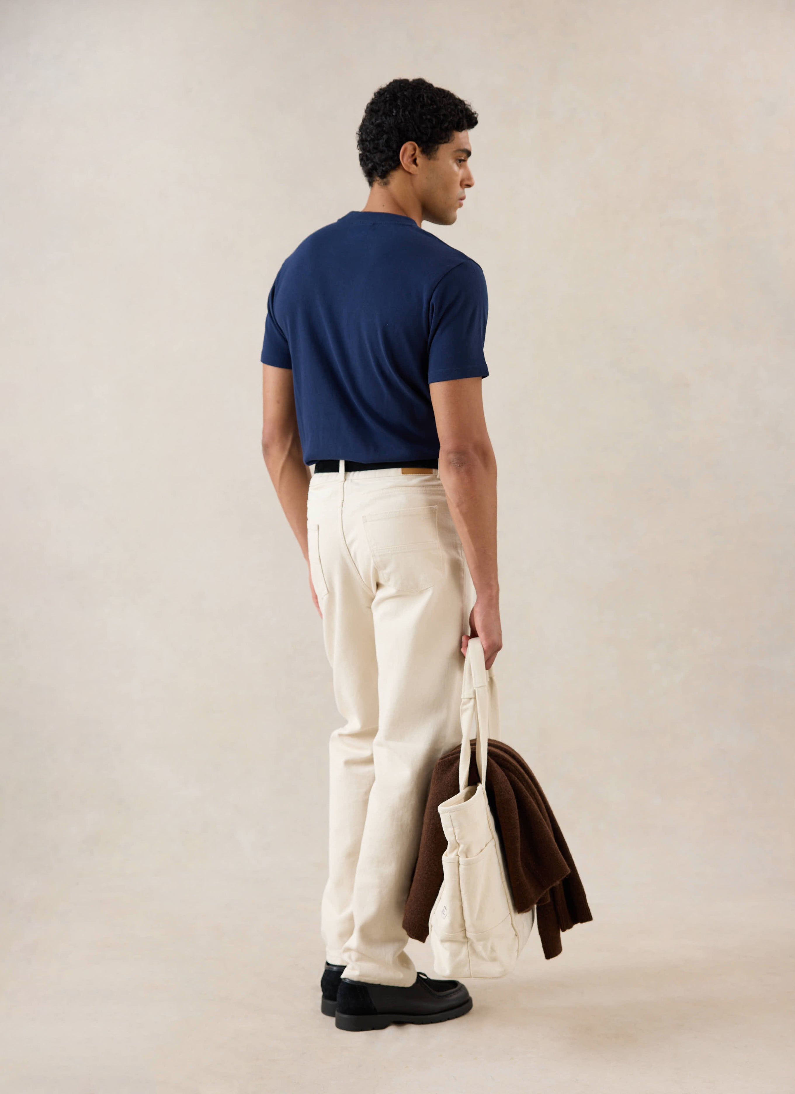 Model wearing Percival's Plain Regular T Shirt in Navy with Percival Cream Jeans.