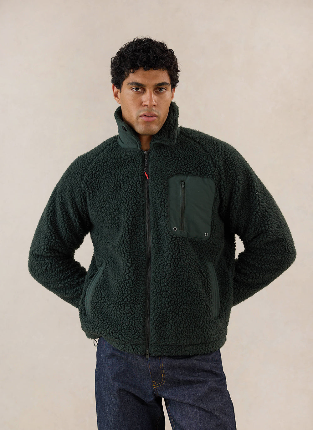 A model wears the forest green wool fleece jacket from Percival, featuring a high collar and chest pocket.