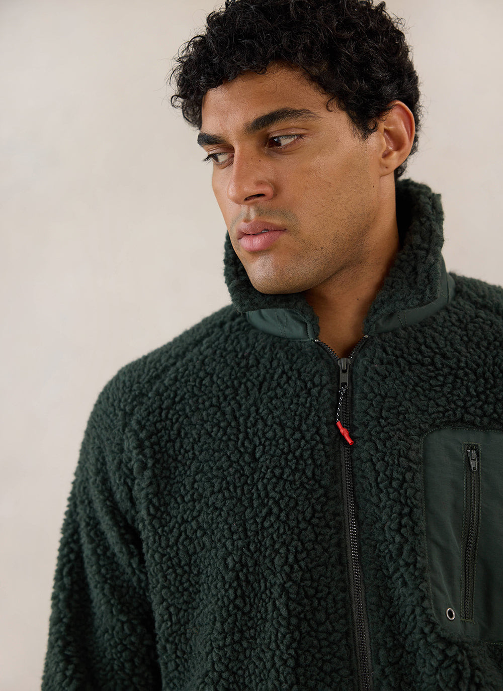 A close-up of a model wearing the Percival forest green fleece jacket, showing the textured wool fabric and zip collar.